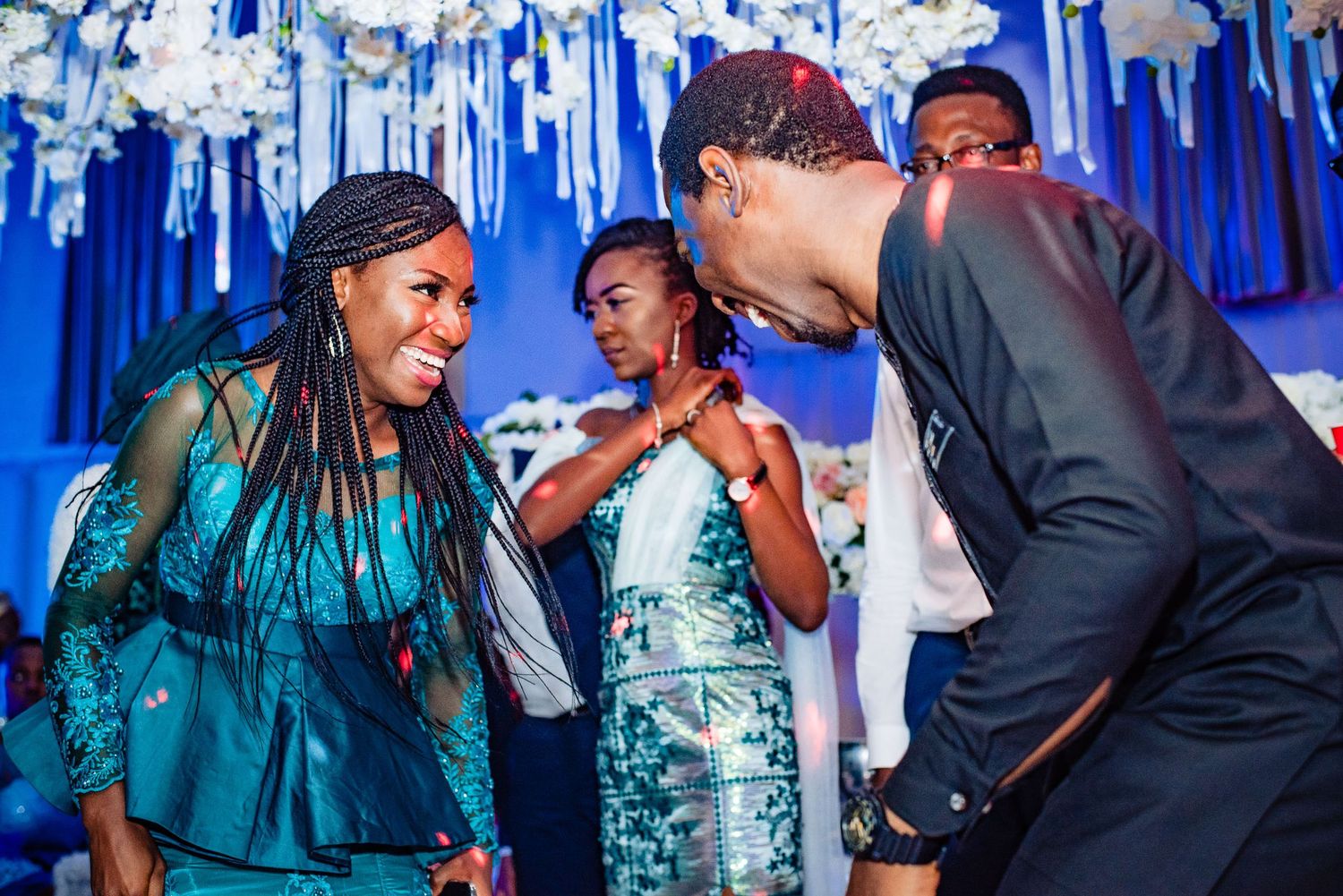 People laughing and dancing at an elegant party with blue decorative streamers hanging from above.