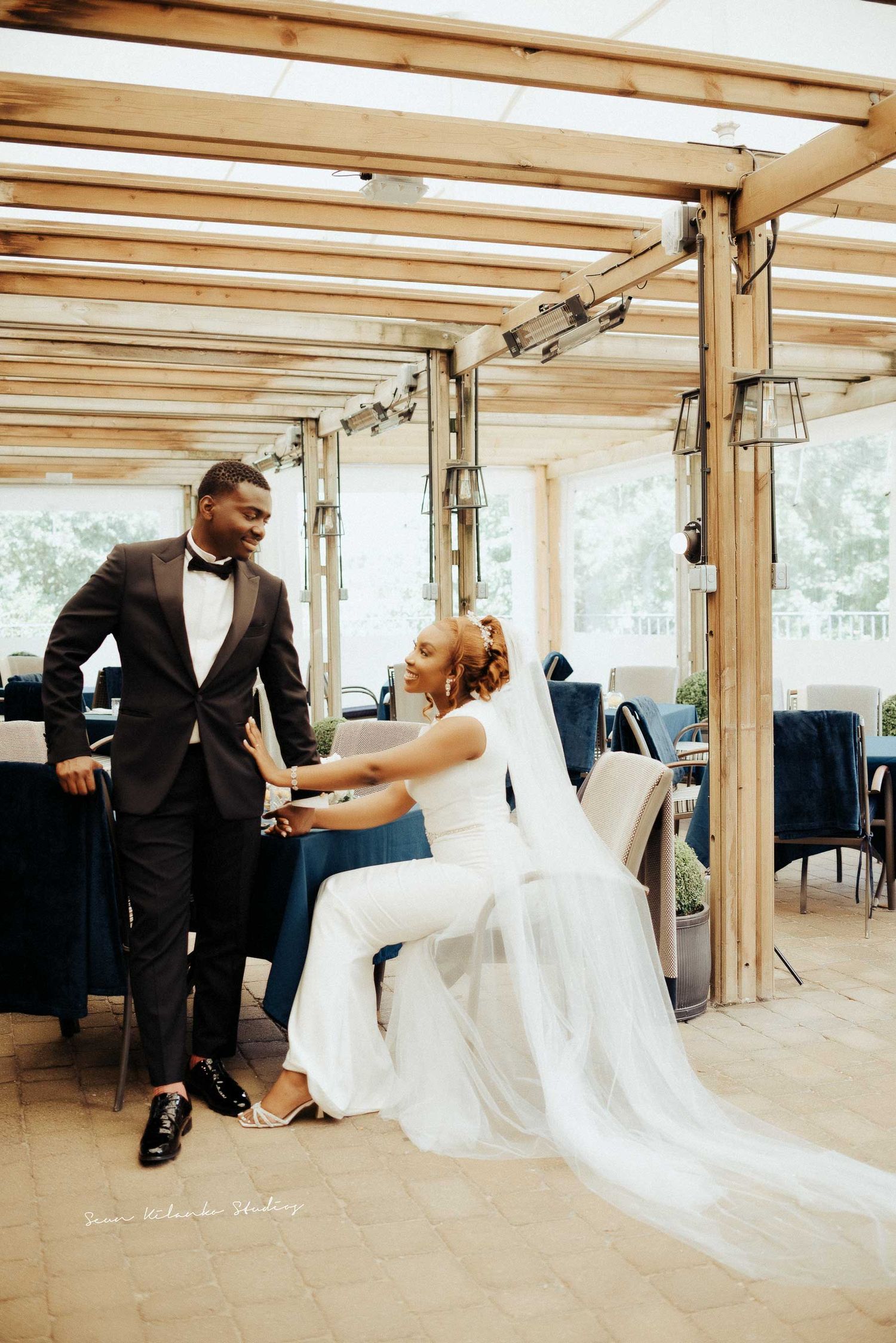 A playful wedding moment captured in a covered outdoor venue with wooden beams.
