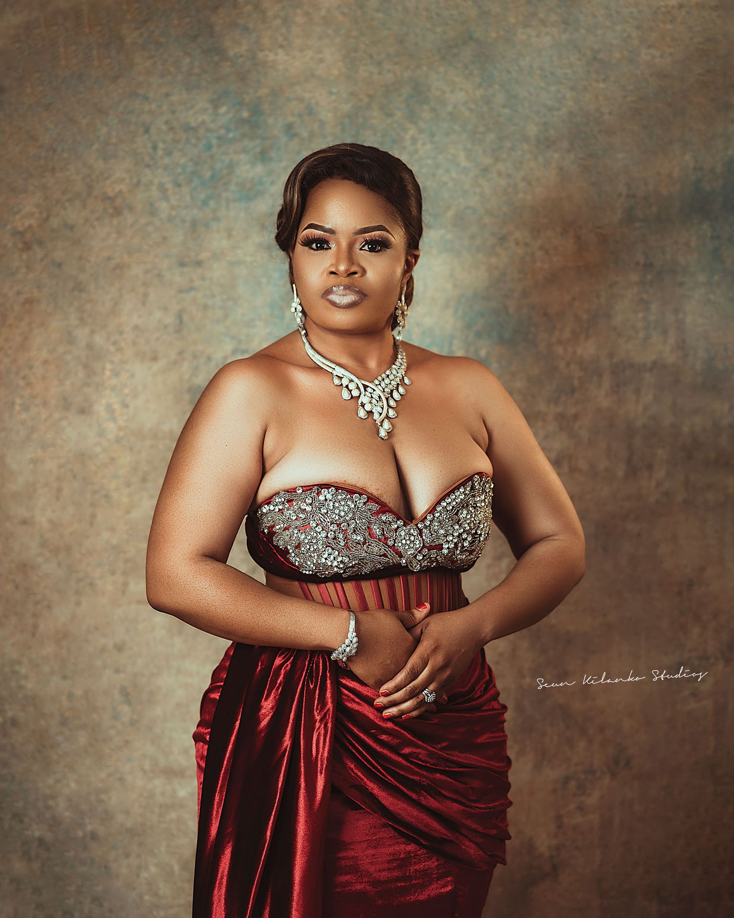 Glamorous studio portrait in a red silk gown with silver bodice and statement jewelry.