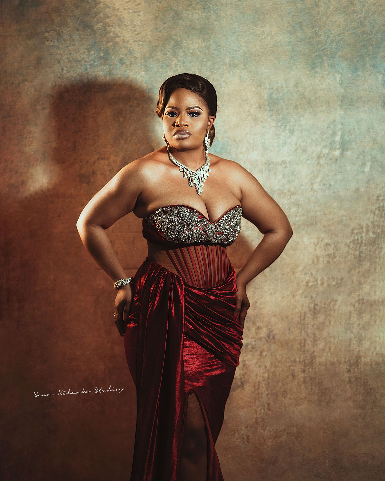 Dramatic portrait in a burgundy and silver evening ensemble with statement crystal necklace.