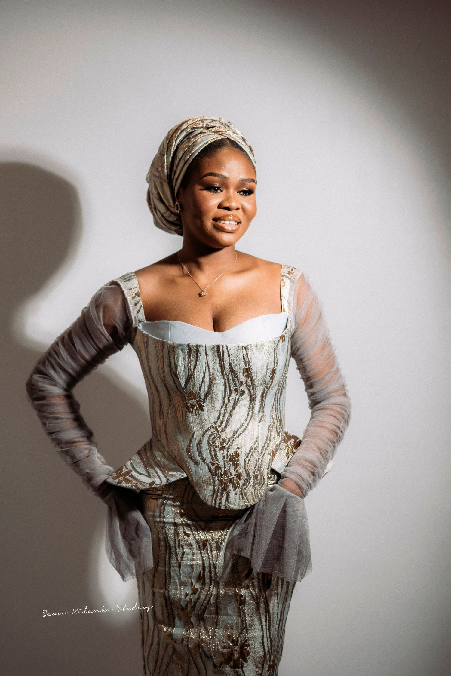 A portrait in vintage-style dress with a marble-patterned corset and headwrap against a white background.
