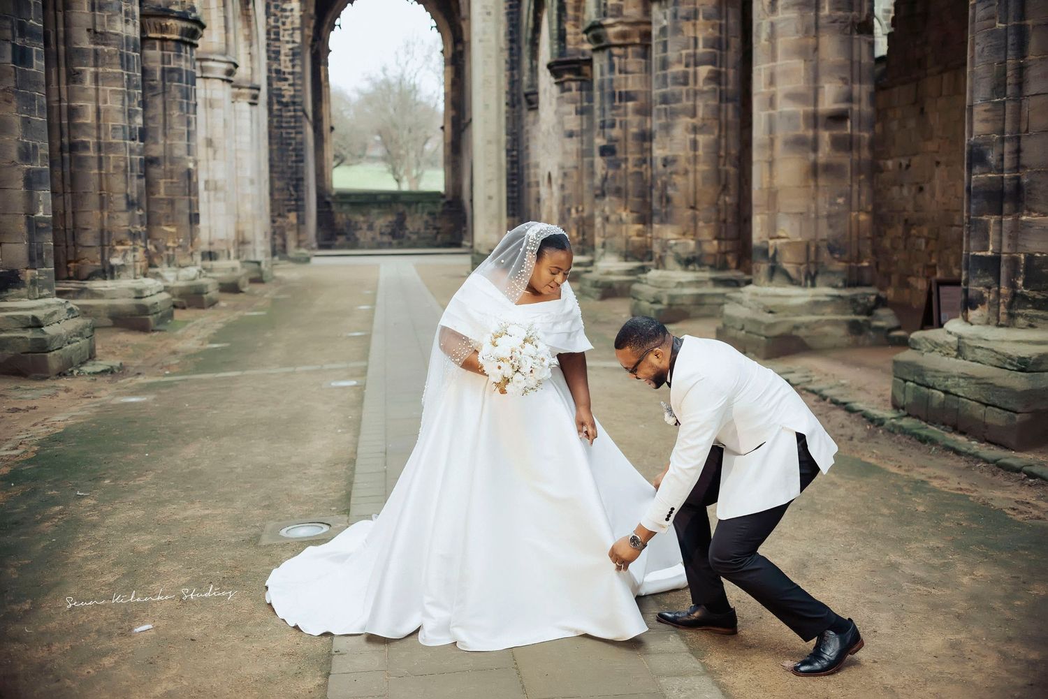 A playful wedding photo showing dance moves under cathedral arches.