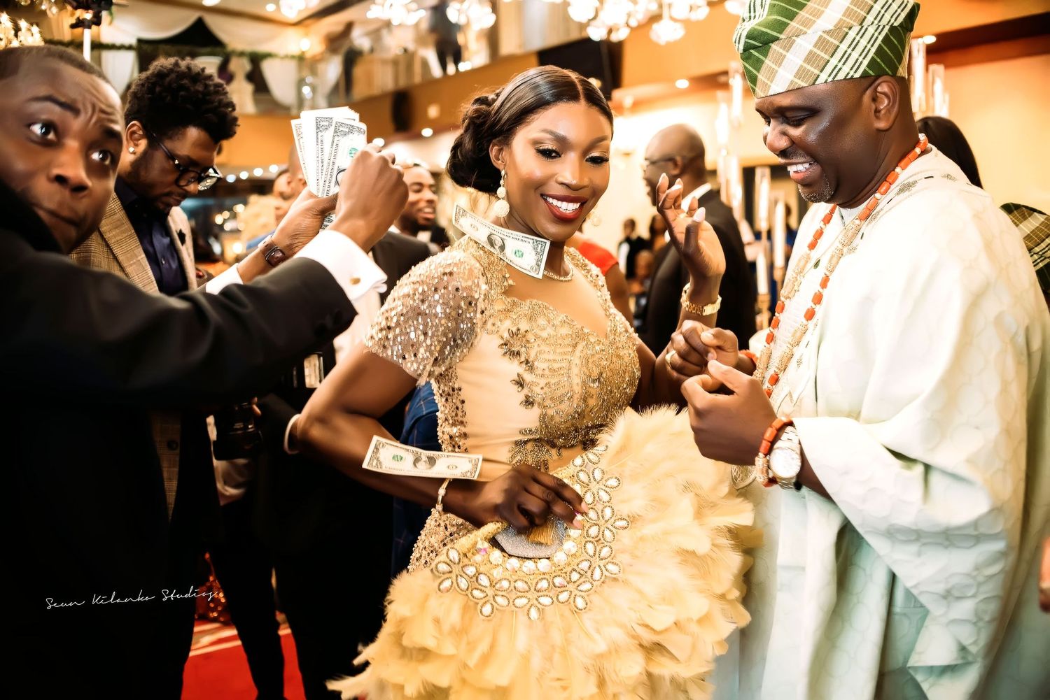 Celebrants in traditional Nigerian attire dance and celebrate at a vibrant wedding reception event.
