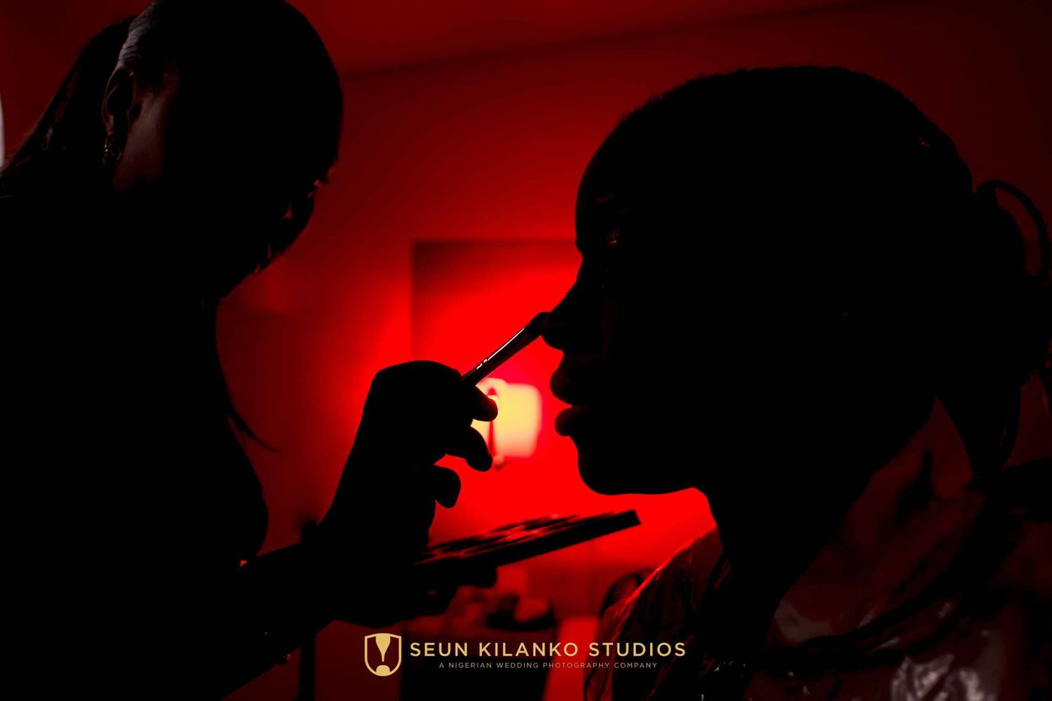 Silhouetted figures in red lighting create a dramatic atmosphere with one person lighting up what appears to be a cigarette.