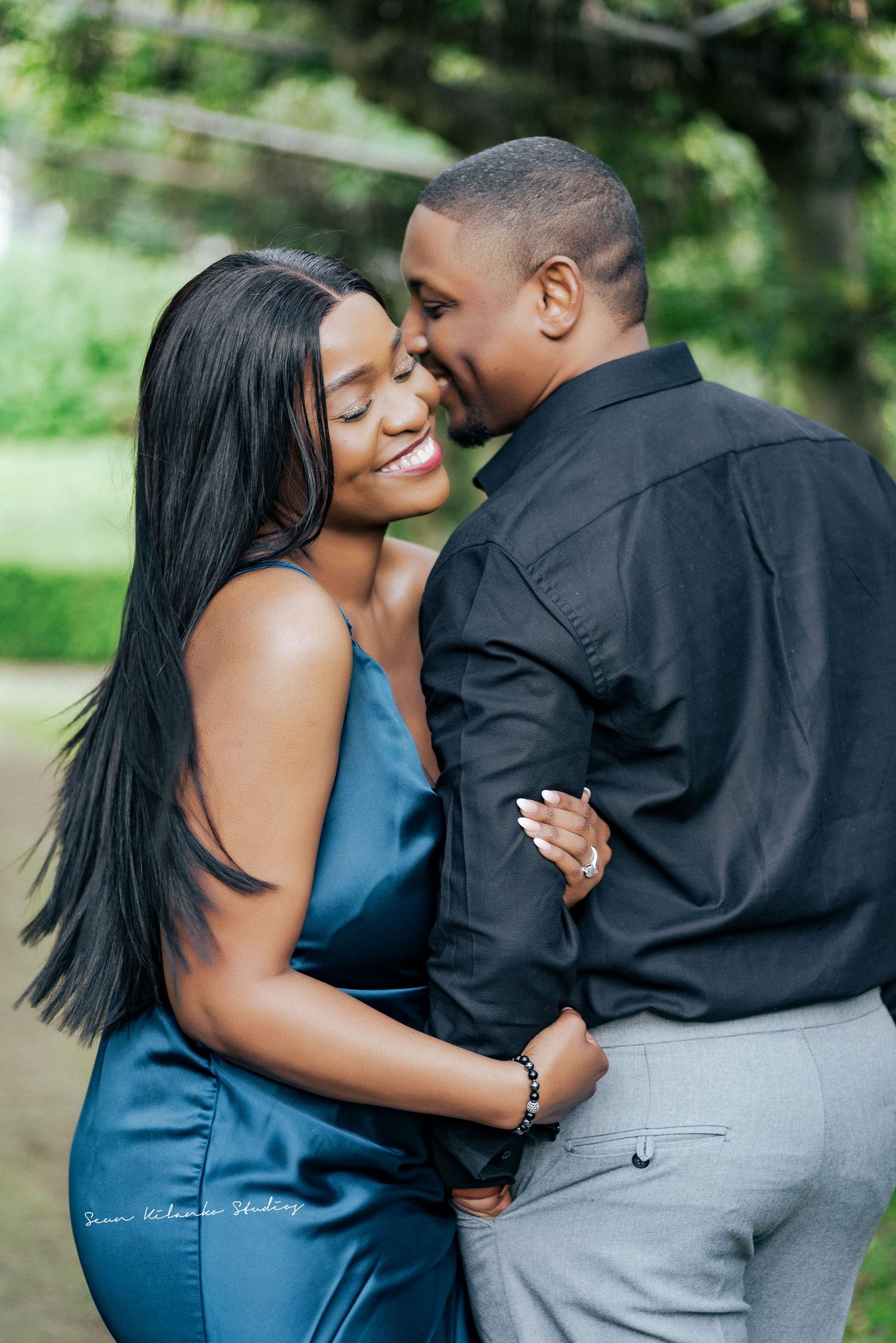 A couple laughs together during an outdoor photoshoot in coordinated outfits.