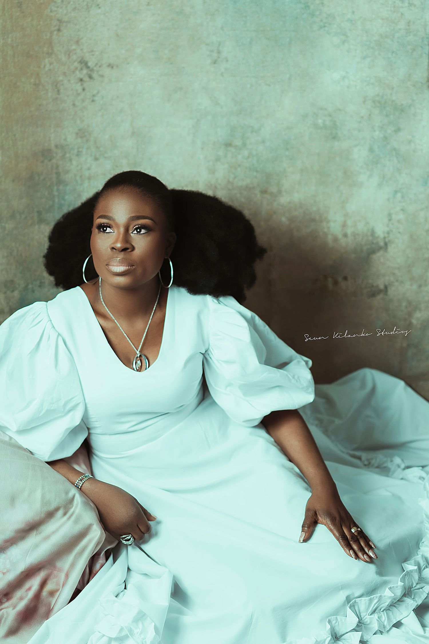 Elegant portrait in white puff-sleeve dress with vintage-inspired styling and natural hair.