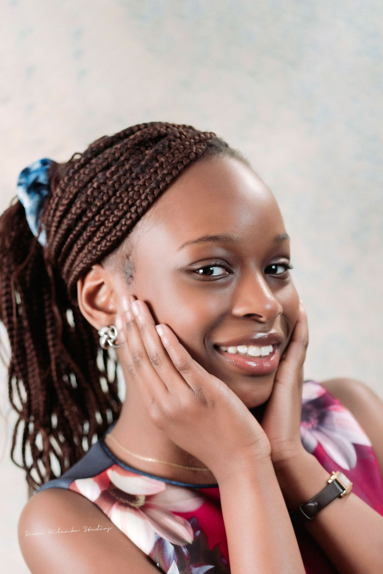 Close-up beauty portrait highlighting braided hairstyle and radiant expression.