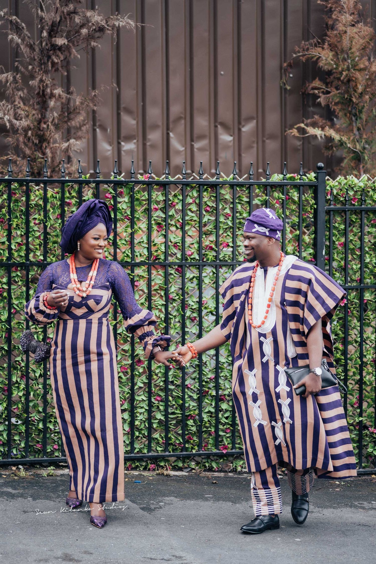 Candid moment of two people in matching striped African formal wear sharing a laugh.