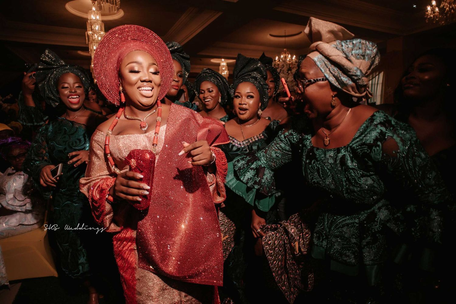 A group of people in traditional Nigerian attire dance and celebrate at what appears to be a festive gathering or party.