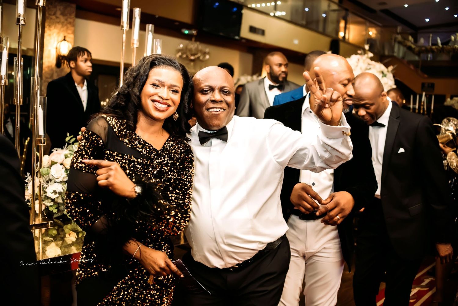Group of well-dressed guests enjoying a celebratory moment at an elegant evening event with warm lighting.