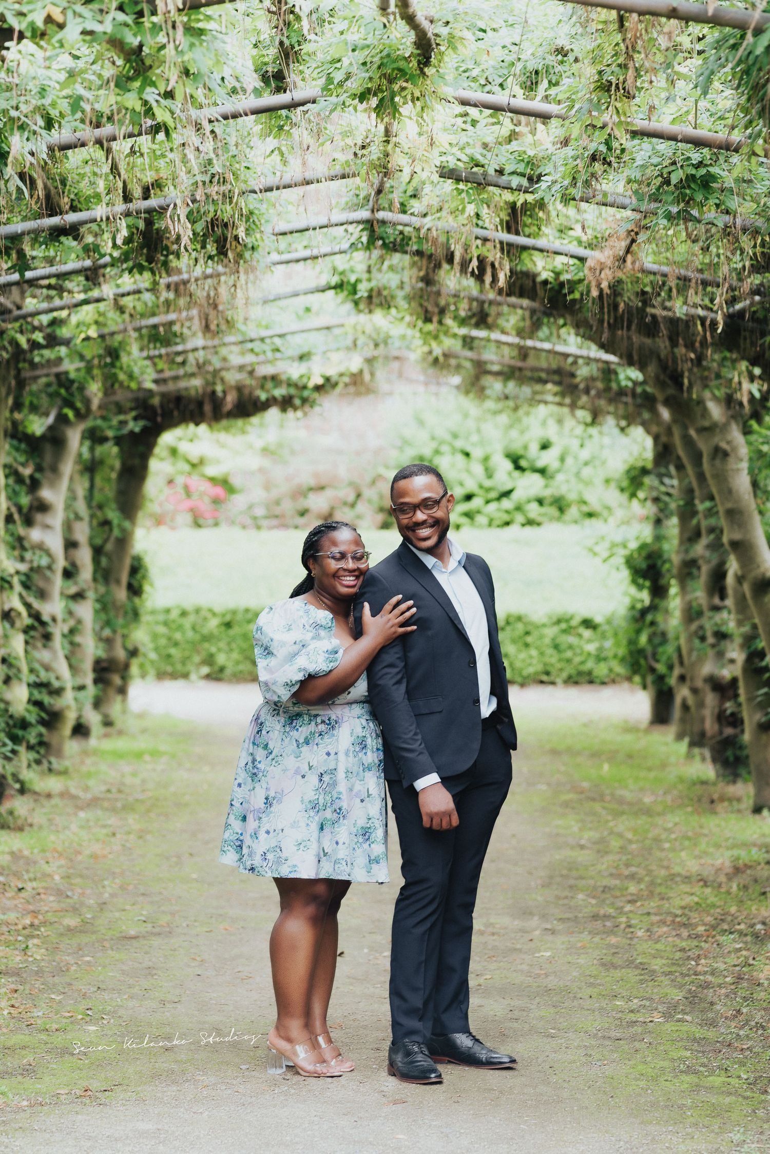 Couple shares intimate moment under vine-covered garden archway.
