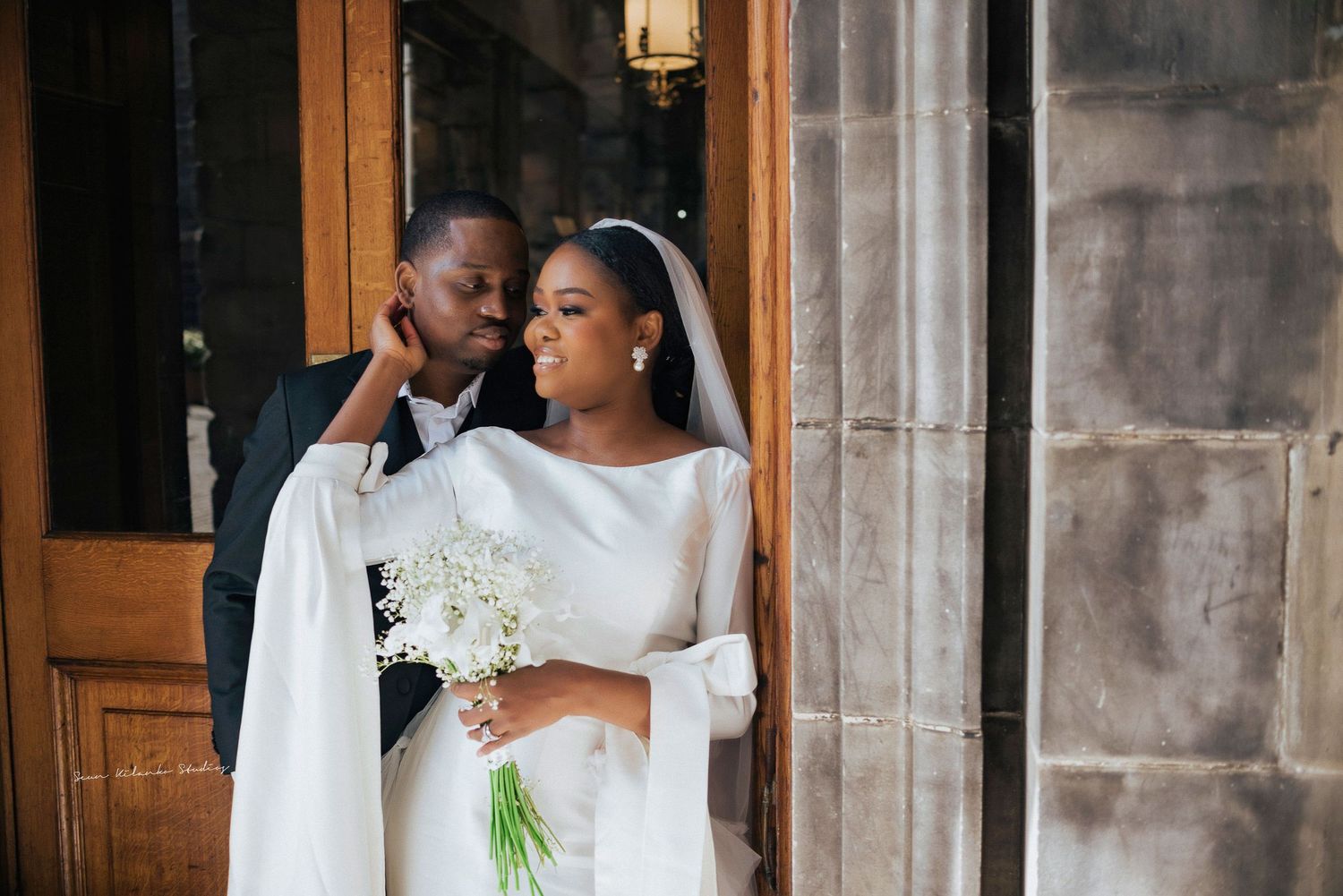 A romantic wedding photography moment captured outside a historic building with stone walls.