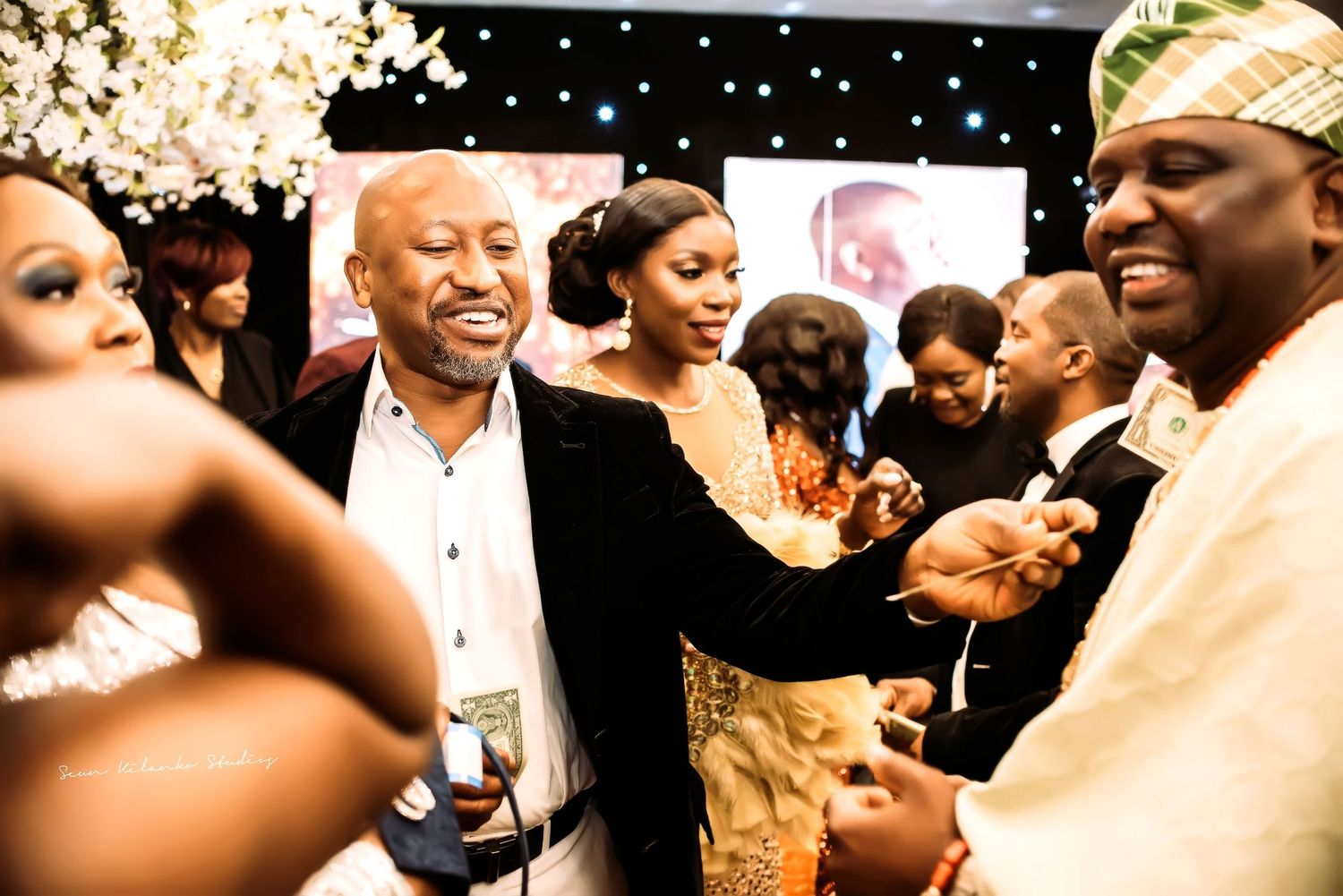 A lively party scene with people laughing and mingling at what appears to be a formal celebration event.