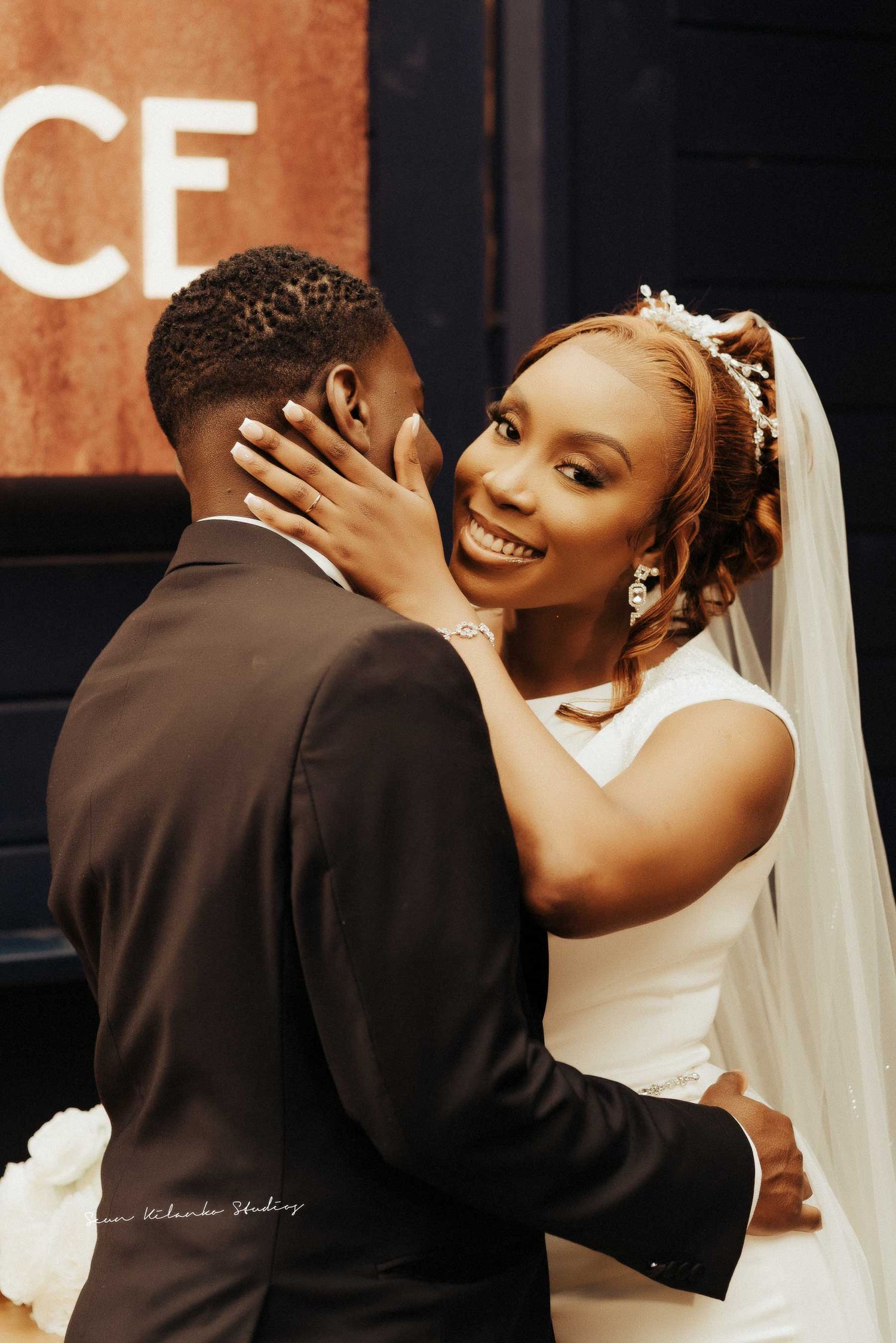 A joyful wedding moment captured as the bride smiles while embracing her groom.