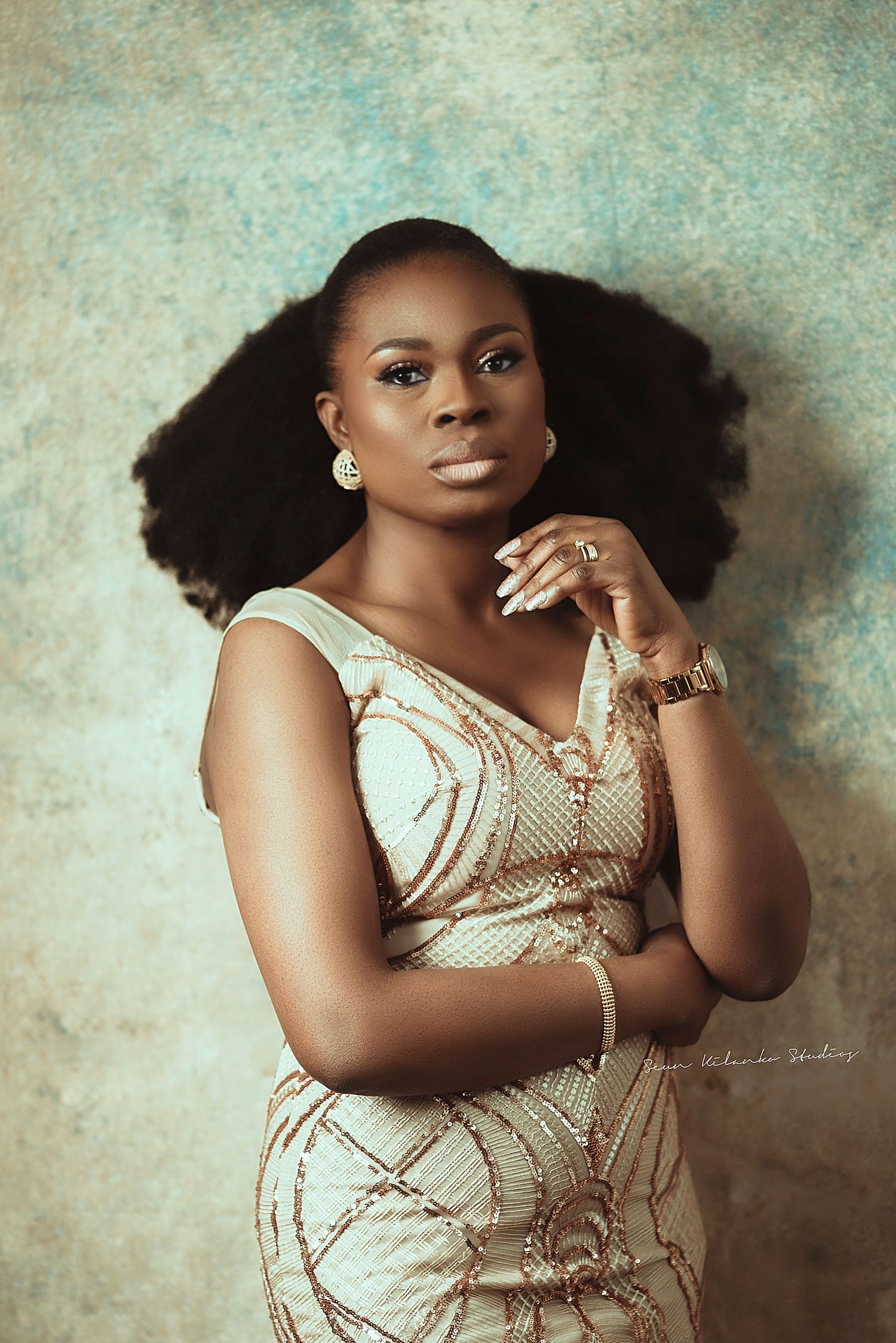 Classic studio portrait in beige patterned dress with statement jewelry.