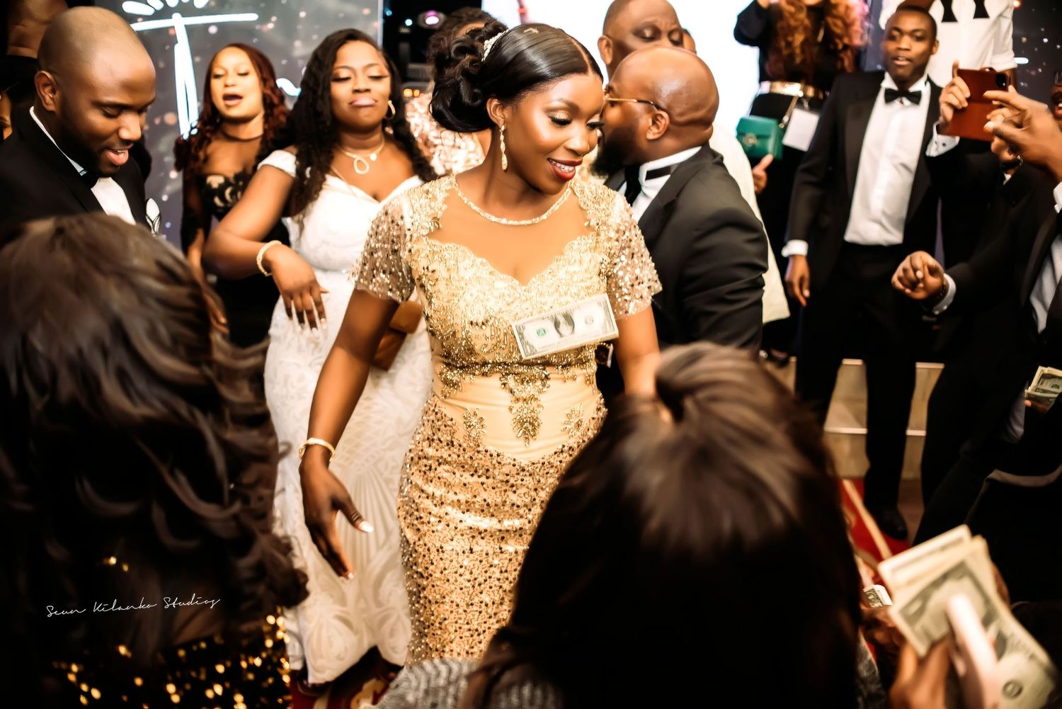 A glamorous wedding celebration with people dancing and having fun in formal attire at a reception.