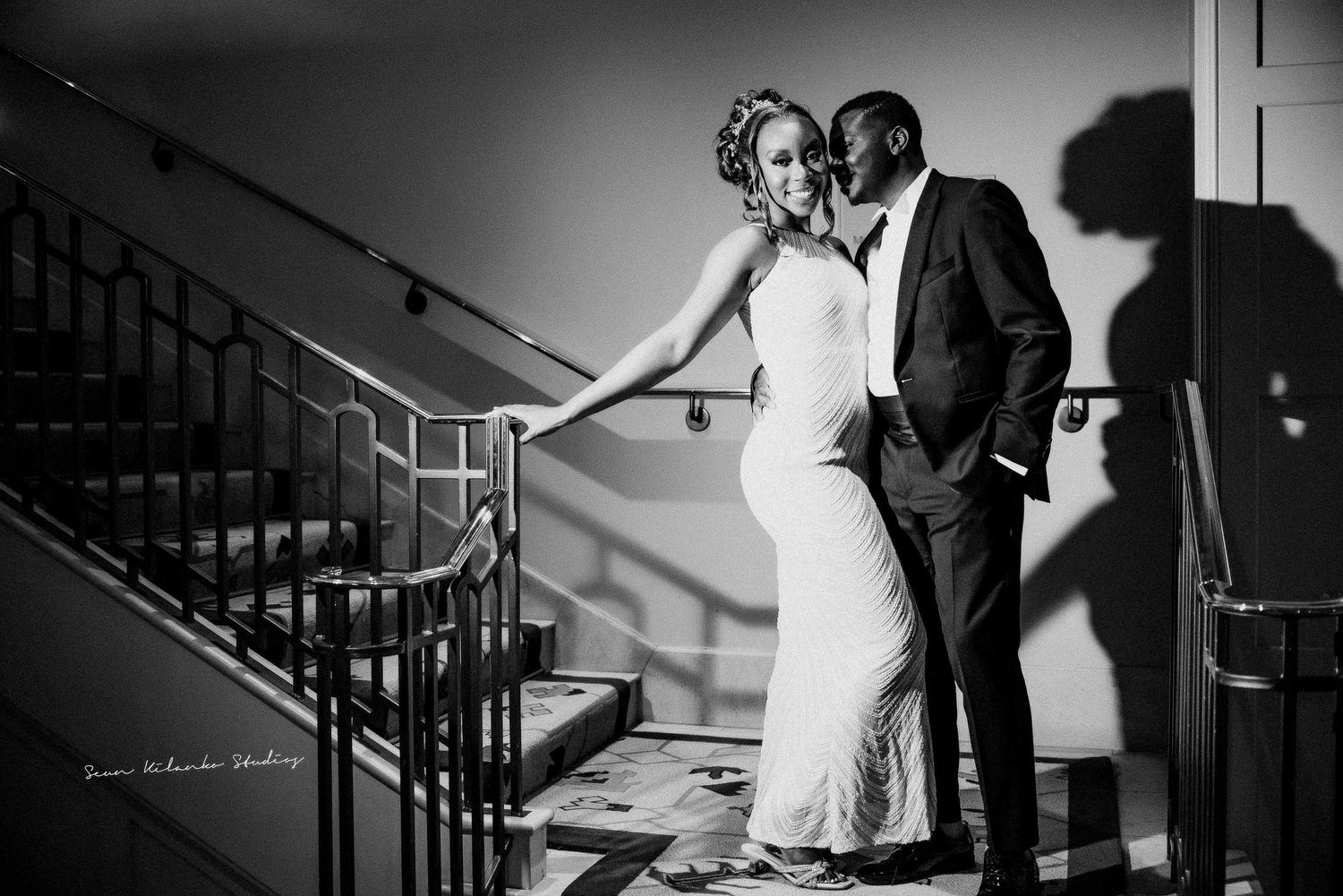 Black and white photo of couple posing dramatically on vintage staircase.