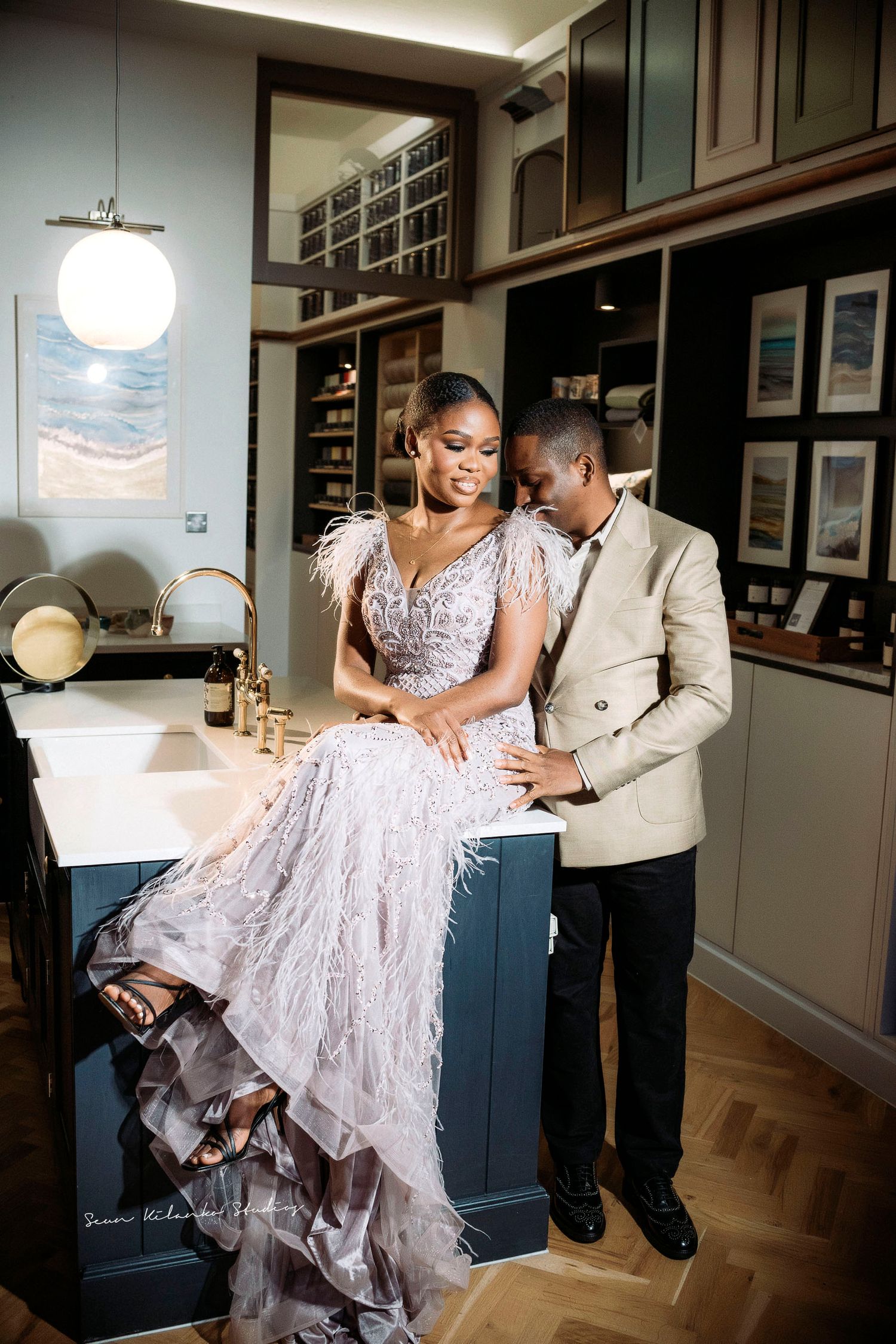Romantic couple moment captured in modern interior with bride seated on counter.