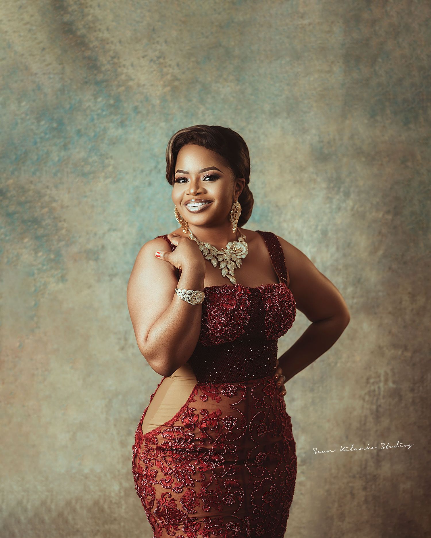 Elegant portrait featuring a burgundy lace gown, statement necklace, and classic styling.
