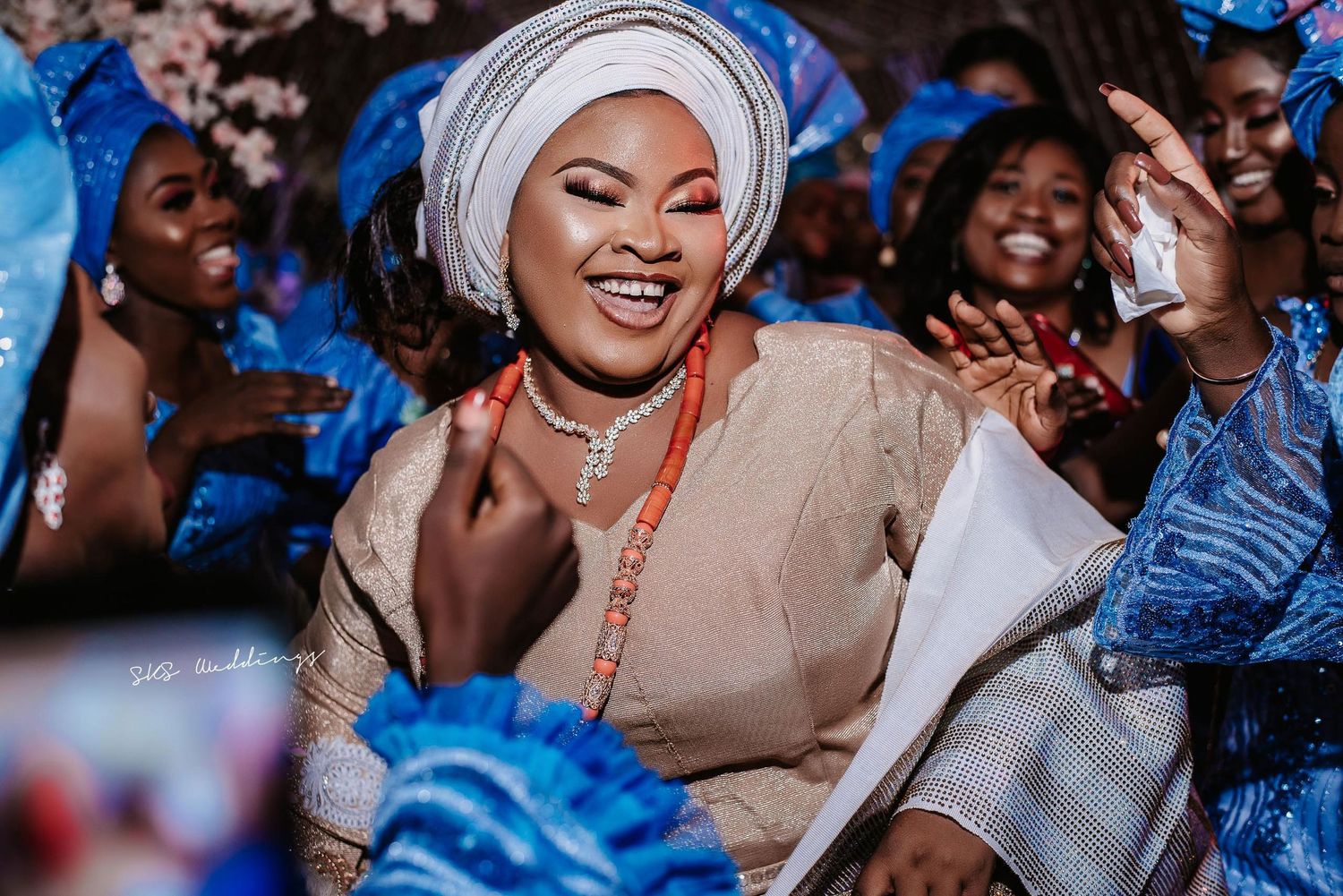 A festive party scene showing guests in traditional African clothing dancing and celebrating with bright expressions.