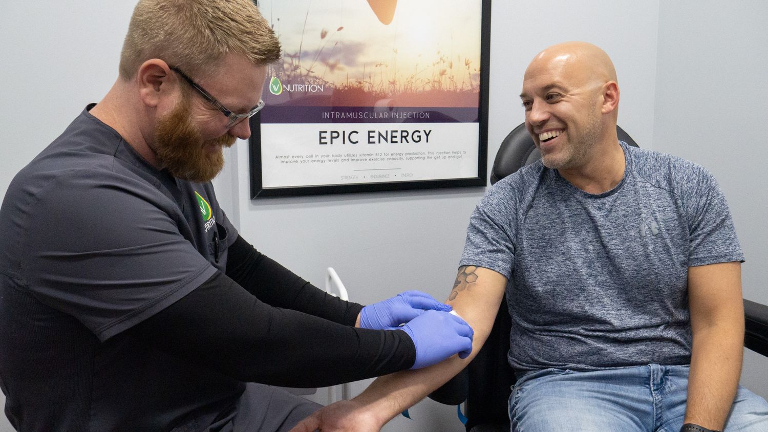 Healthcare professional in blue gloves drawing blood from smiling male patient in modern medical clinic.