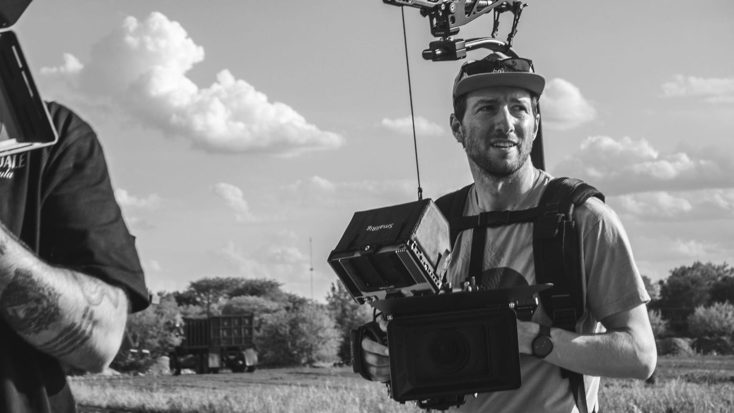 Filmmaker operating camera stabilizer on outdoor set in black and white photo.