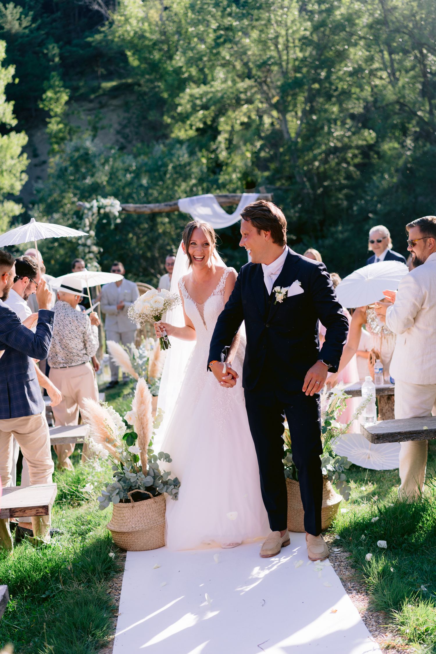 Wedding ceremony recessional on an outdoor white aisle runner surrounded by guests.