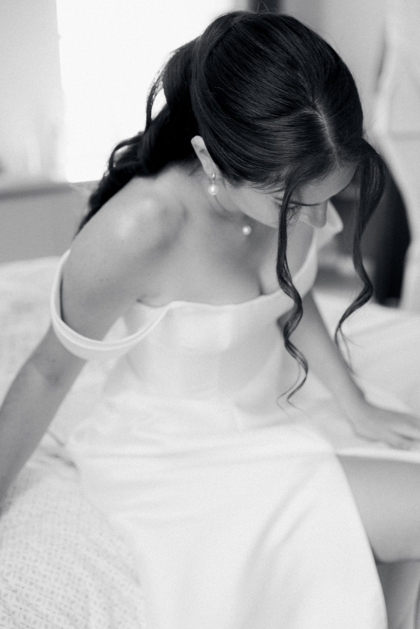 A person in a white shirt is writing or studying at a desk in a bright, minimalist setting.