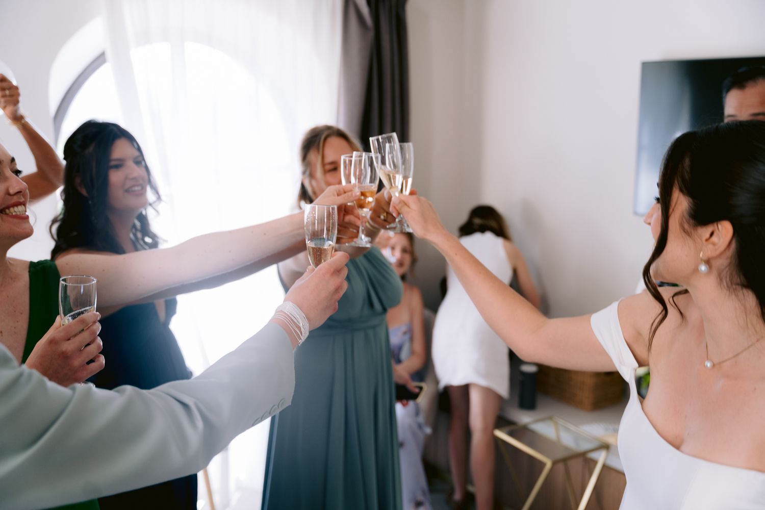 People raise champagne glasses in a celebratory toast during a wedding reception.