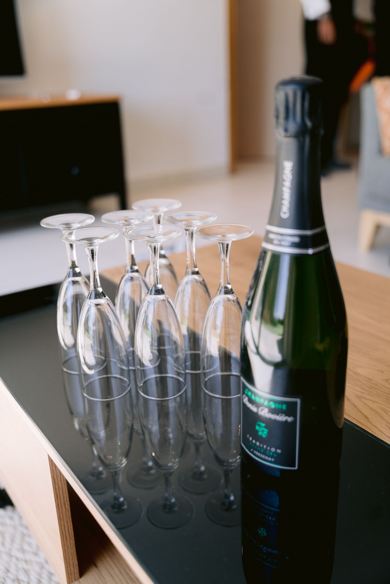 Champagne flutes and bottles arranged on a dark surface with soft lighting and shallow depth of field.