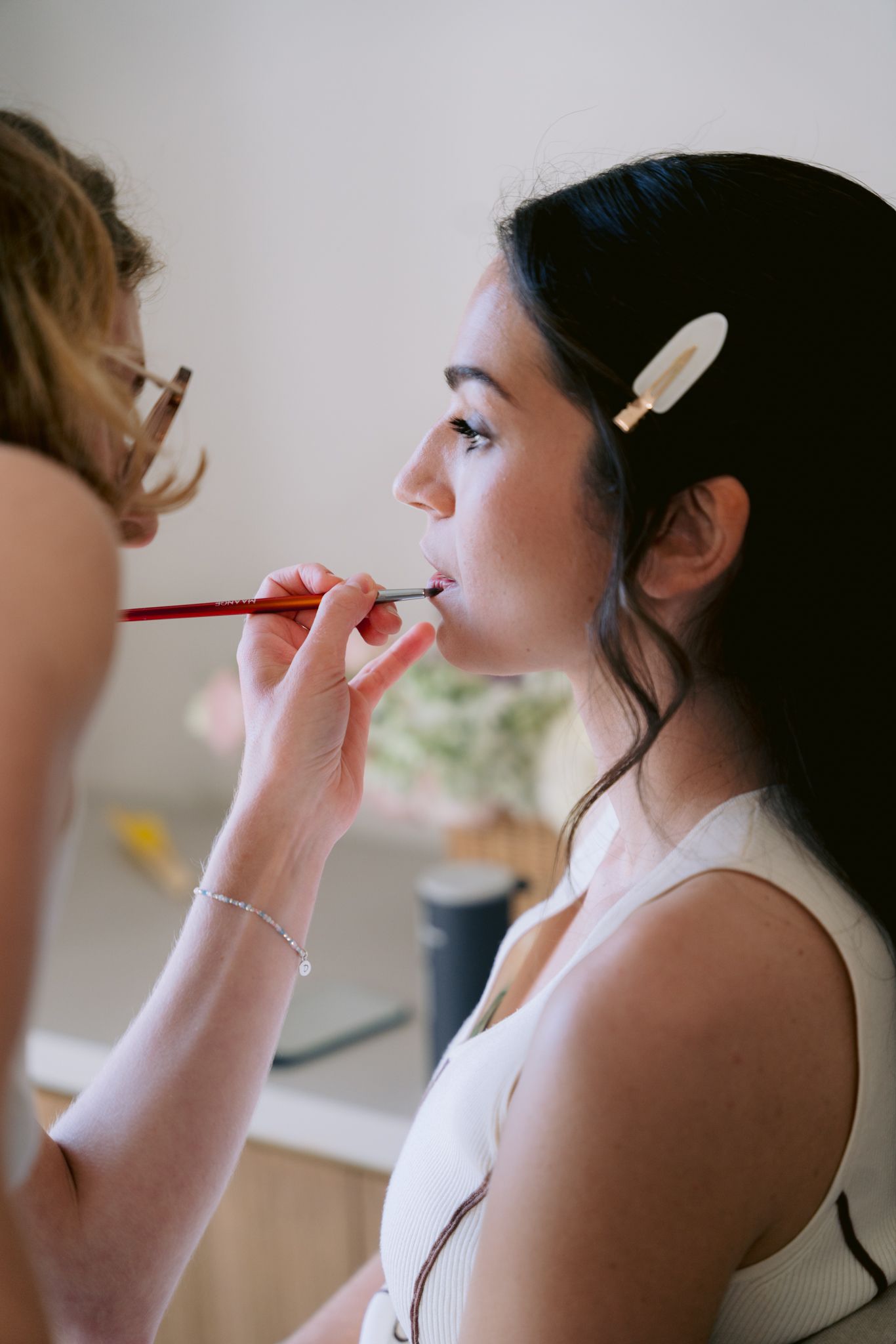 Makeup artist applying cosmetics to a client's face in a sequence of four similar photos.