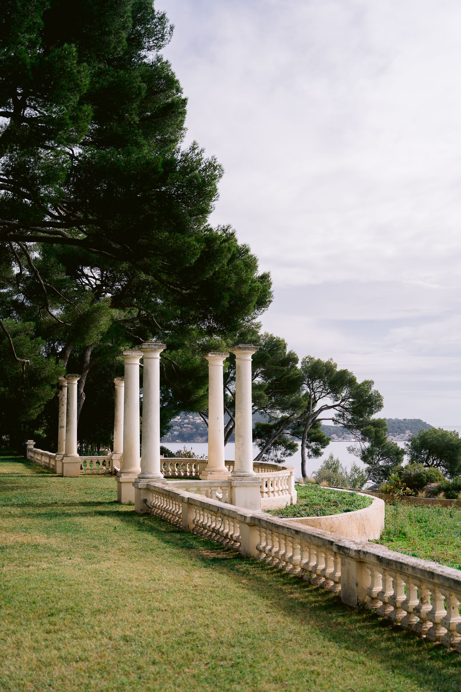 Elegant stone balustrade with classical columns overlooking a serene coastal landscape.