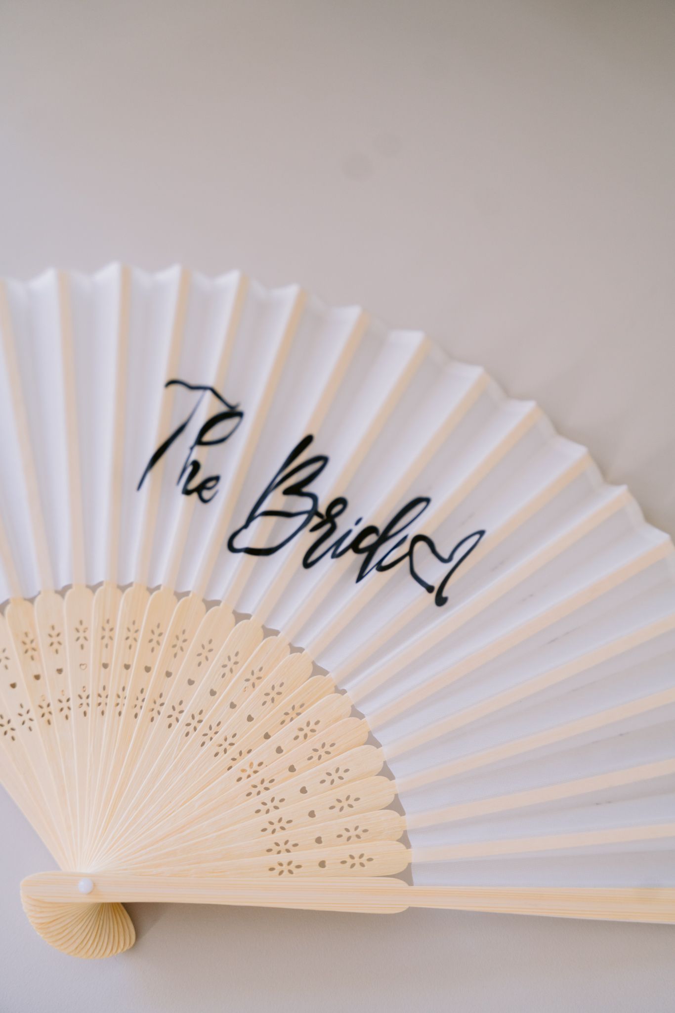 A sequence of white folding fans with wooden frames shown at different angles against a light gray background.