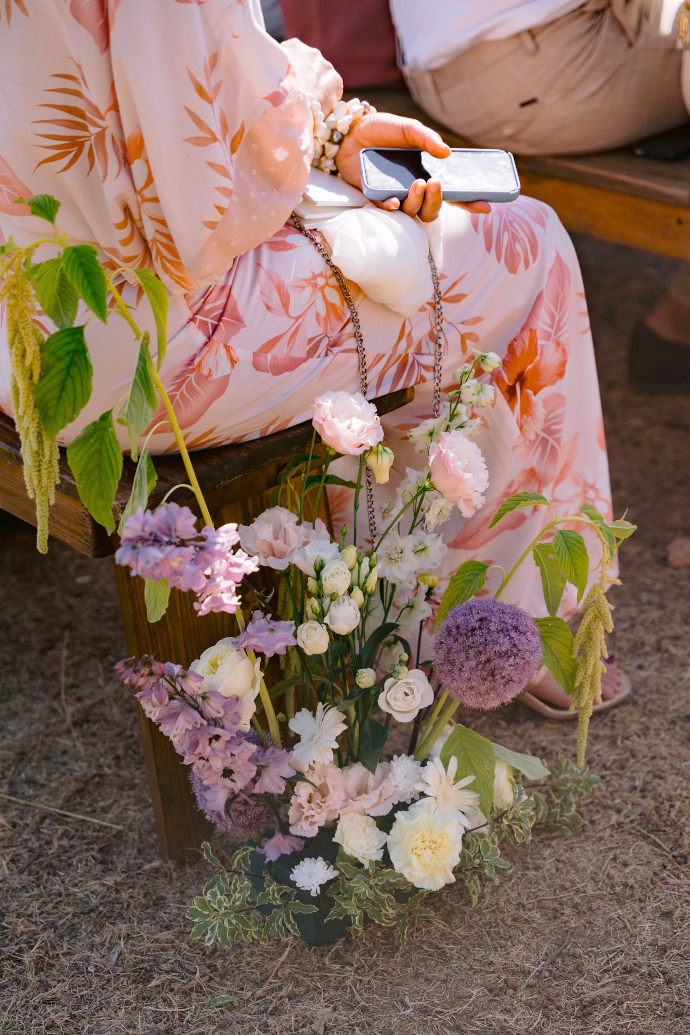 Delicate floral arrangement with pink and white blooms nestled against a soft fabric backdrop with botanical prints.