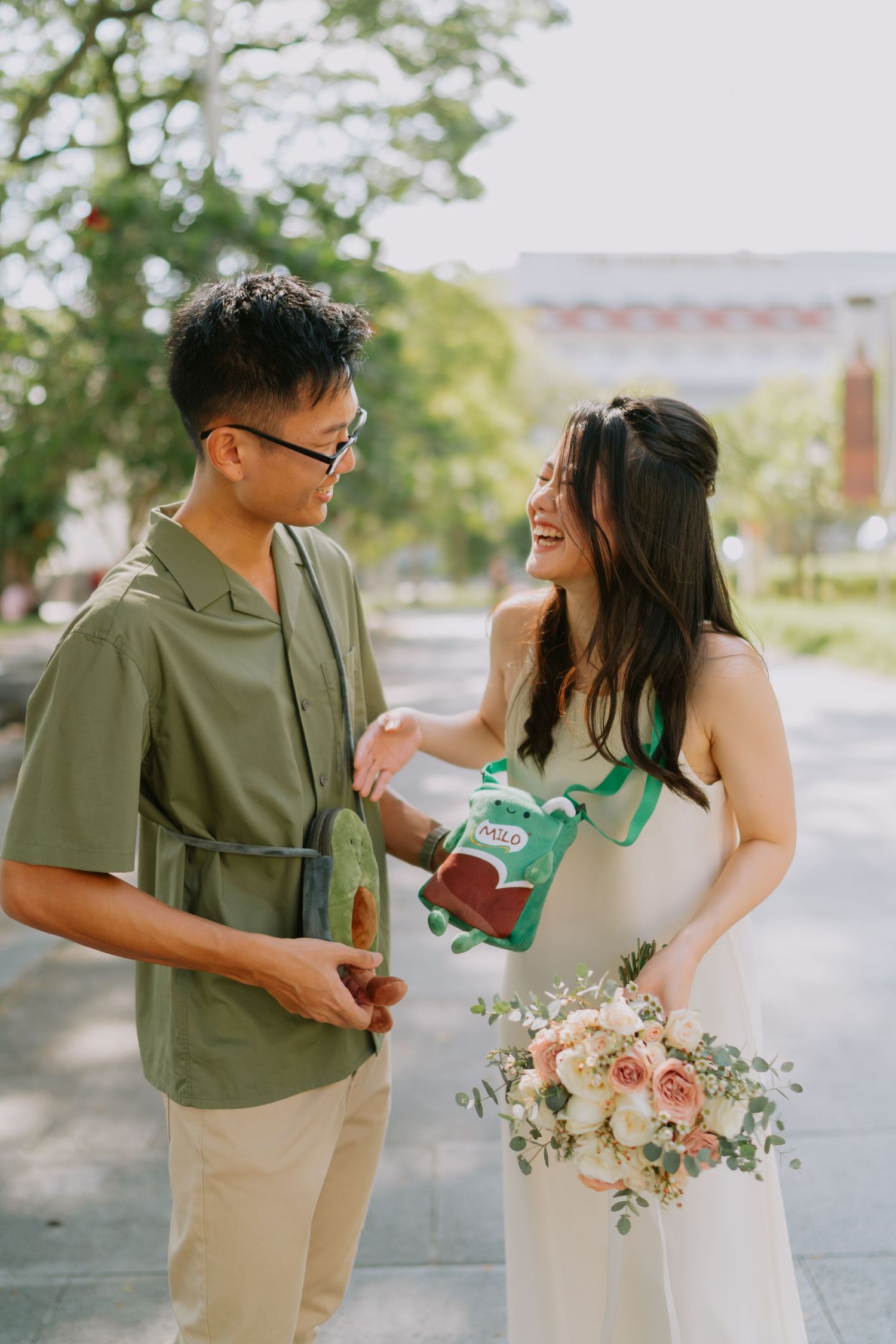 Laughing couple sharing snacks outdoors during fun casual pre-wedding photo session in Singapore.