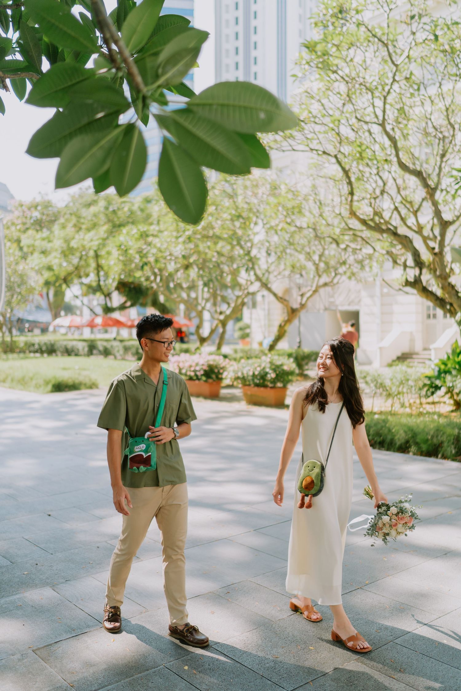 Young couple walking and smiling at each other in a sunny garden park.