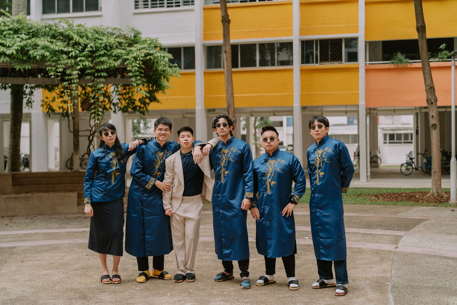 Group of seven people posing outdoors in matching blue traditional Vietnamese ao dai outfits.