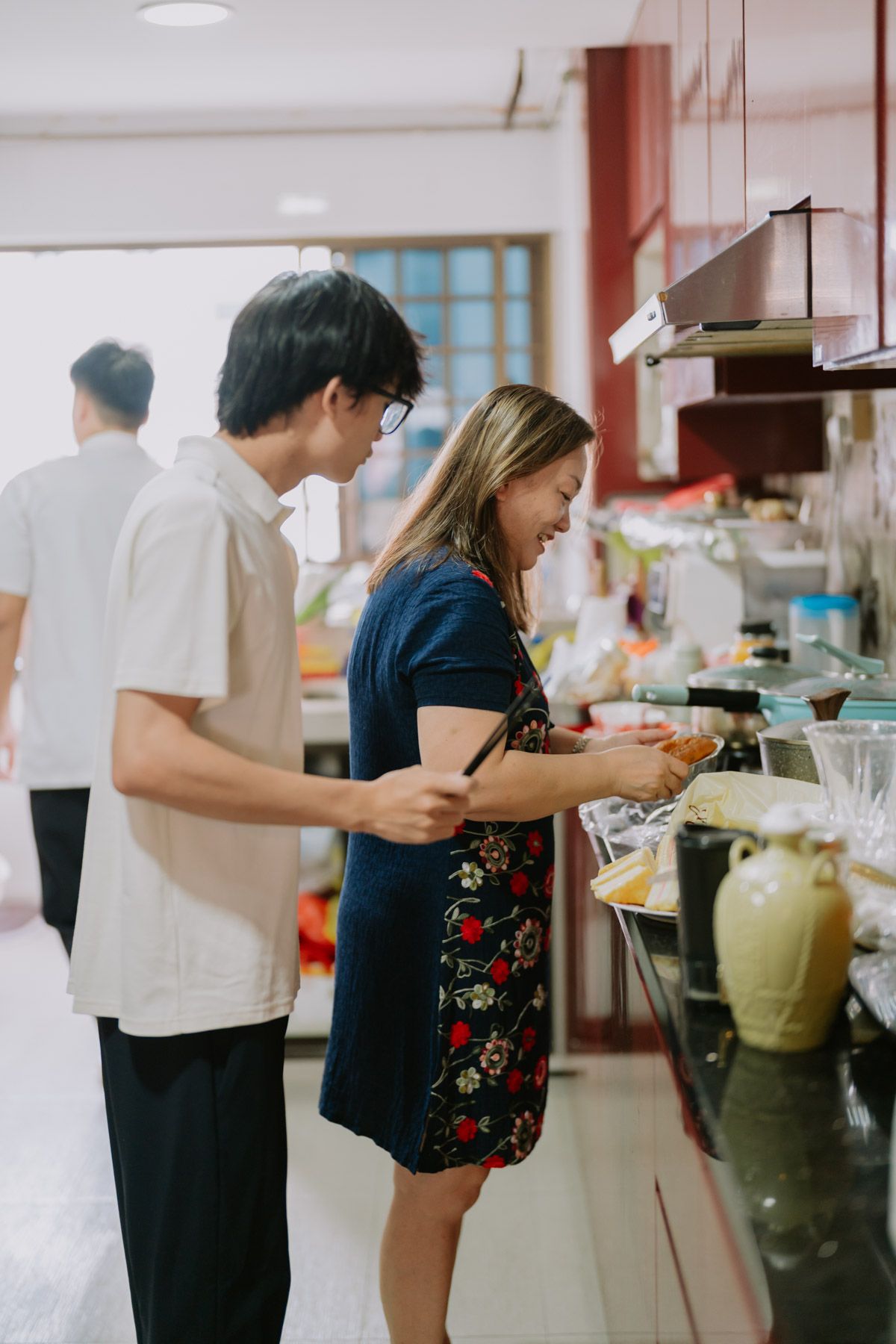 Two people serving food at a buffet counter in a bright Asian restaurant setting.