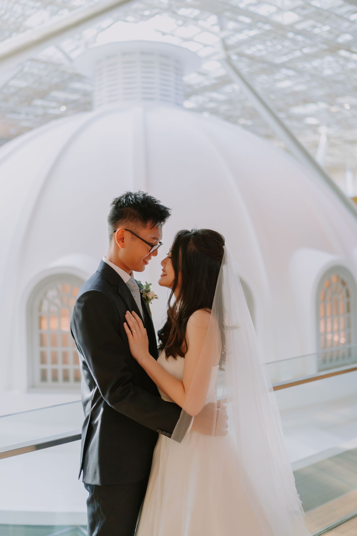Bride and groom sharing an intimate moment in front of a white domed architectural backdrop.