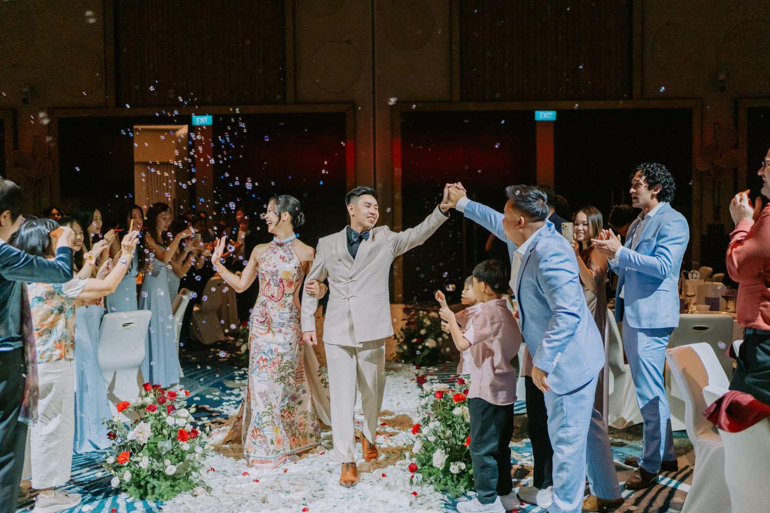 Bride and groom walk down the aisle as guests celebrate with confetti at an elegant wedding reception.