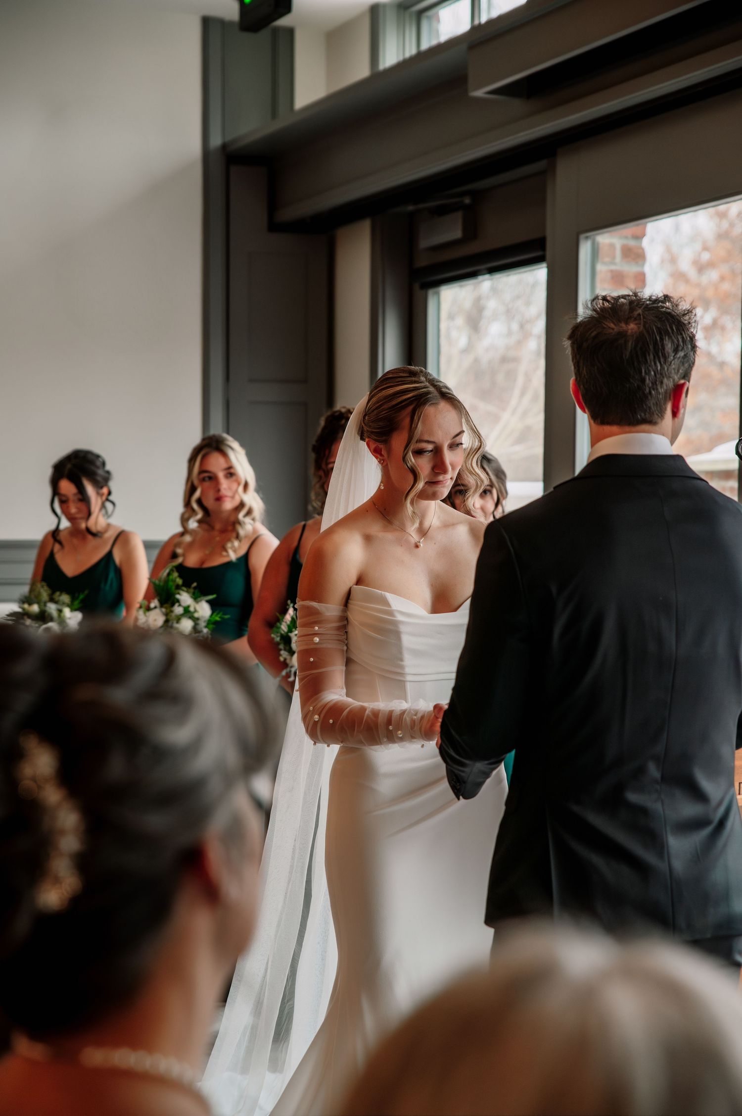 In a collage of five frames, a couple shares an emotional first look moment in a sunlit indoor venue.