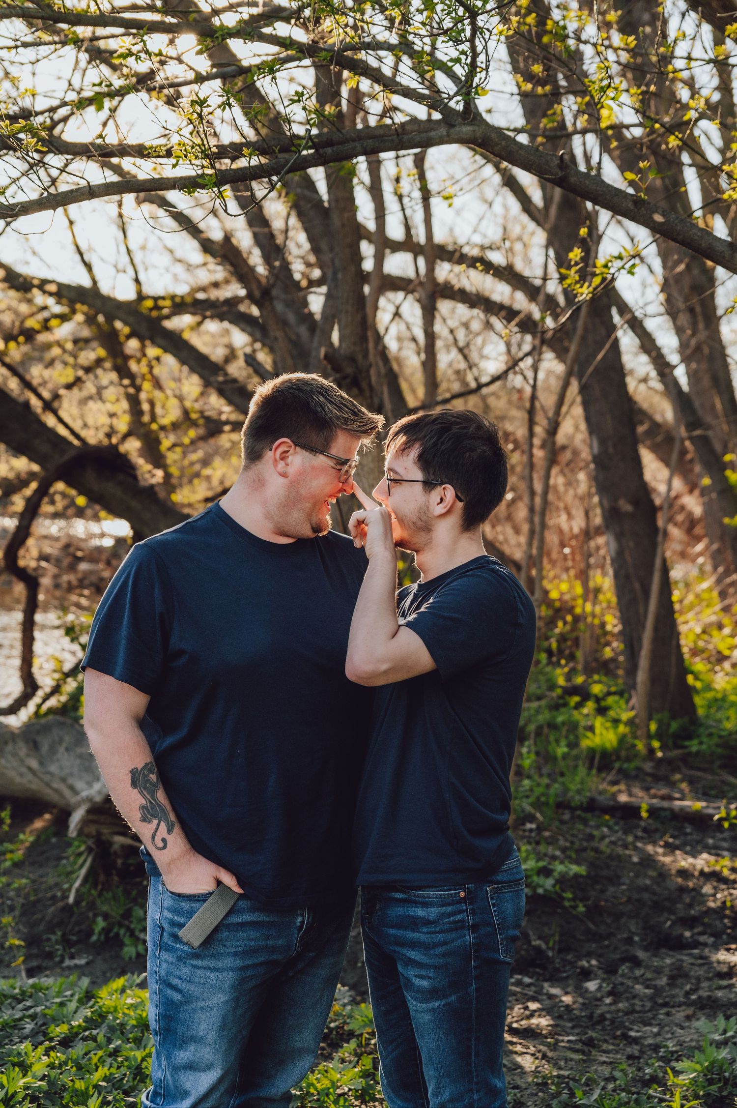 A couple sharing an intimate moment among trees in an autumn woodland setting.