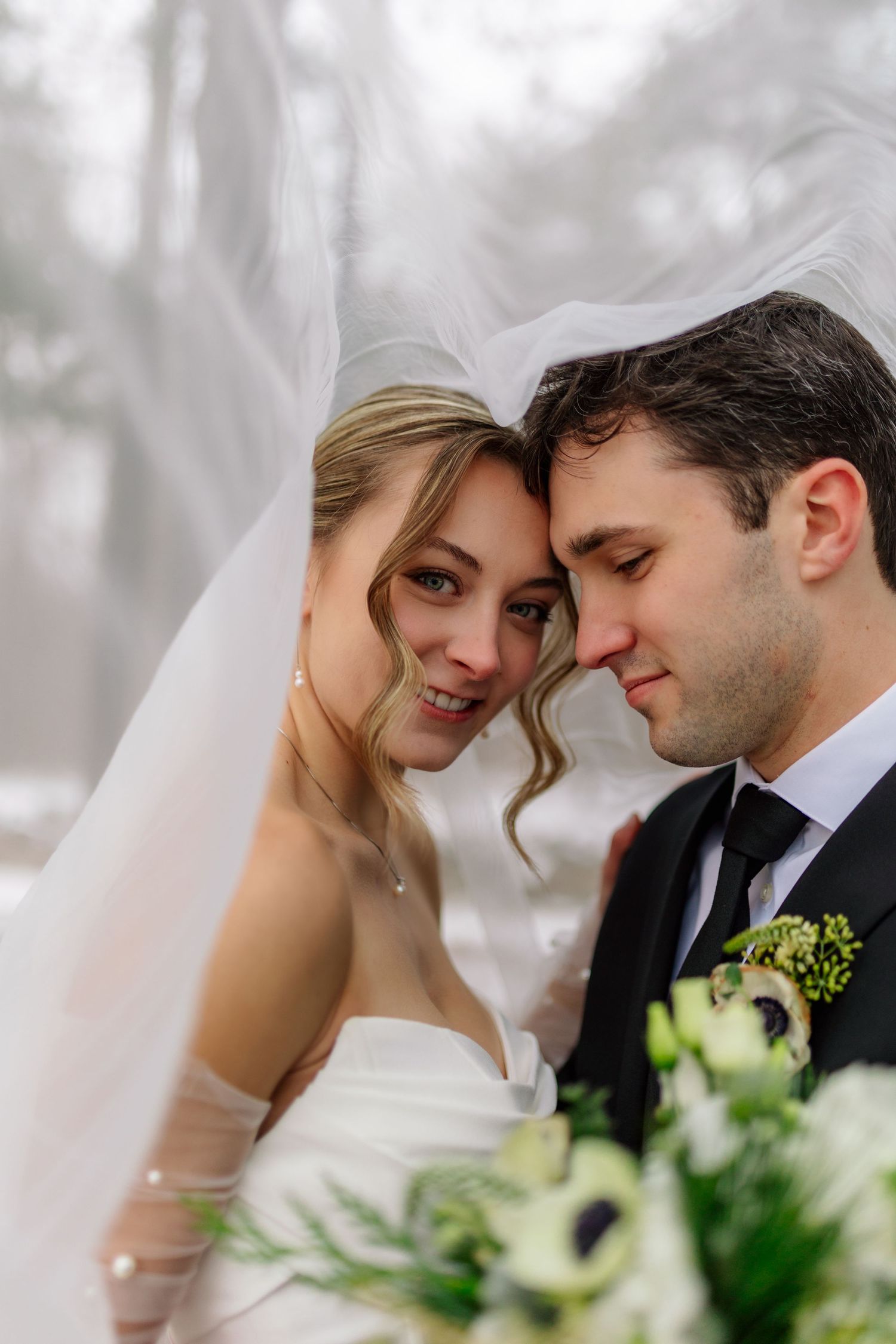 A romantic wedding portrait of a couple sharing an intimate moment among greenery and soft lighting.