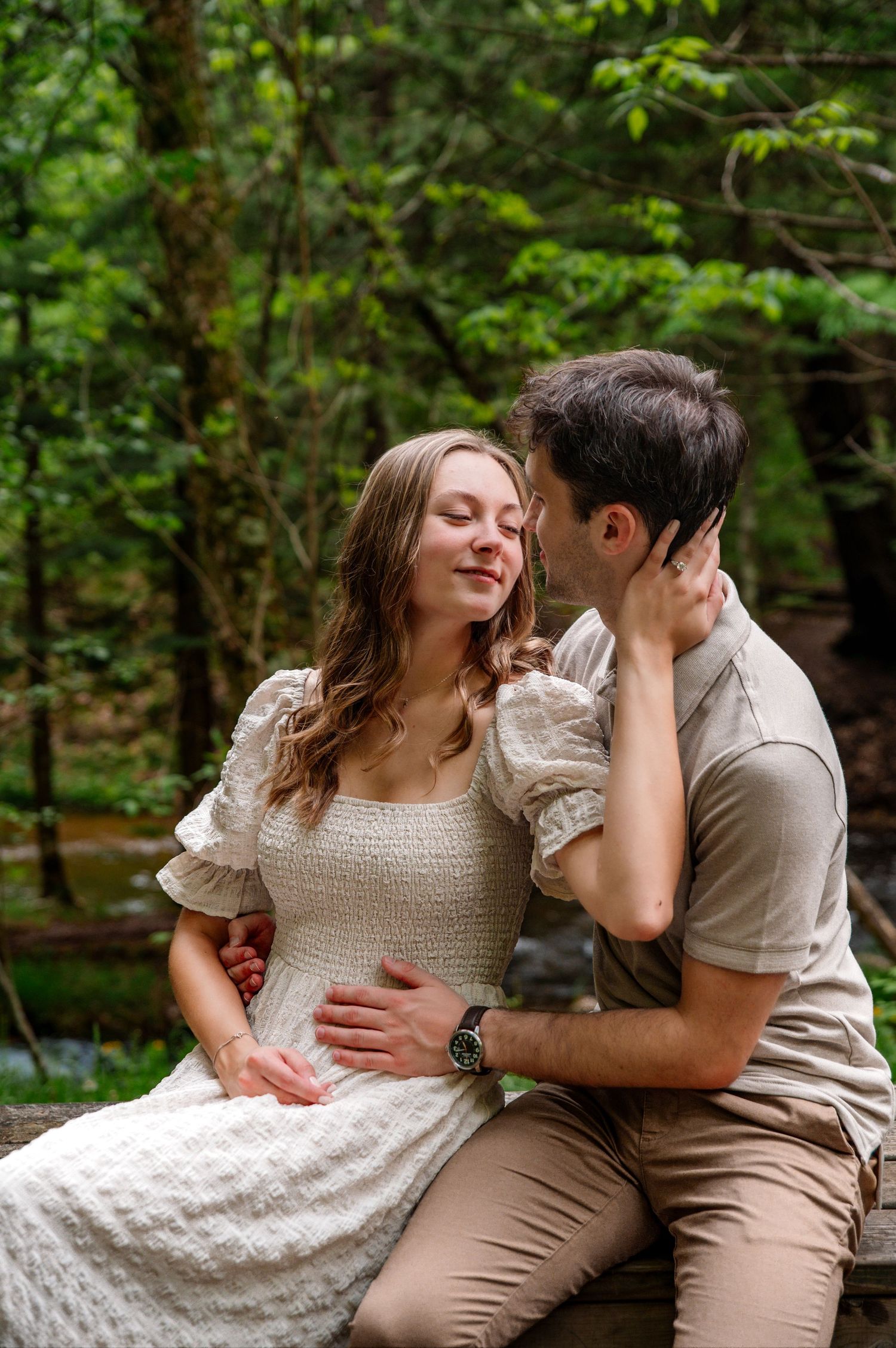 A romantic moment captured in a lush forest setting with natural lighting.