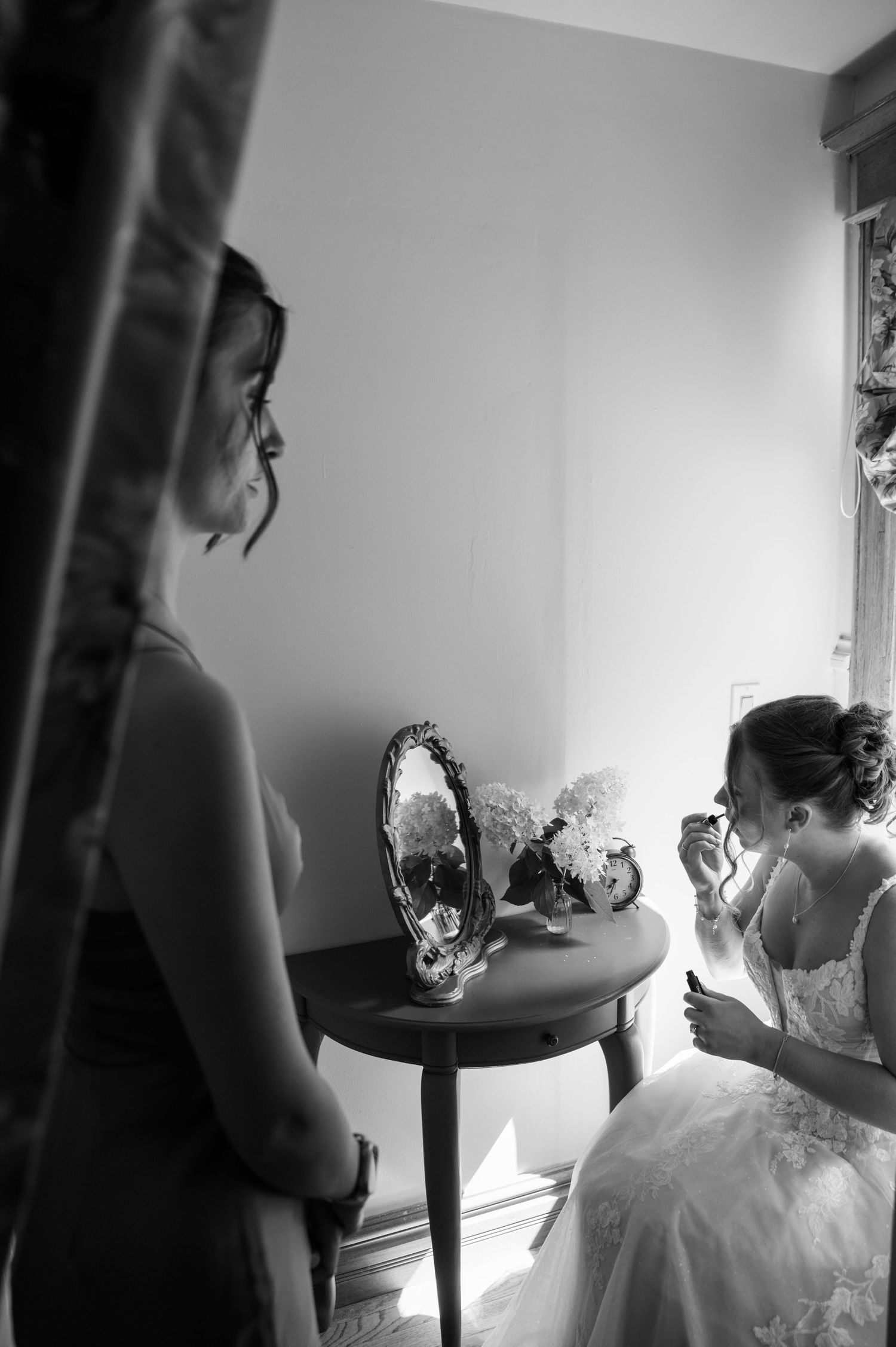 Black and white artistic sequence showing a bride getting ready in her wedding dress against a light-filled room.
