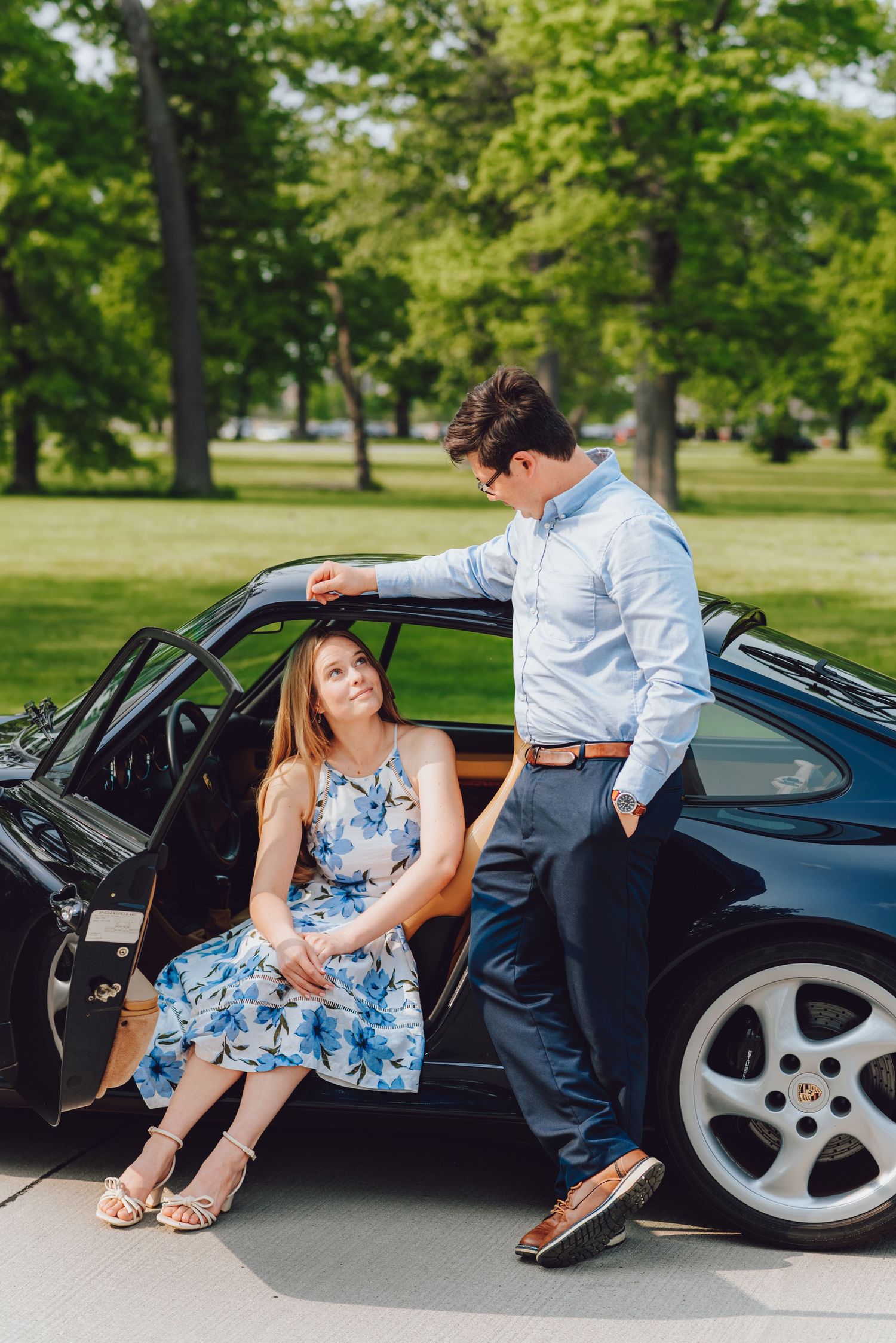A classic black sports car parked in a lush green park setting.