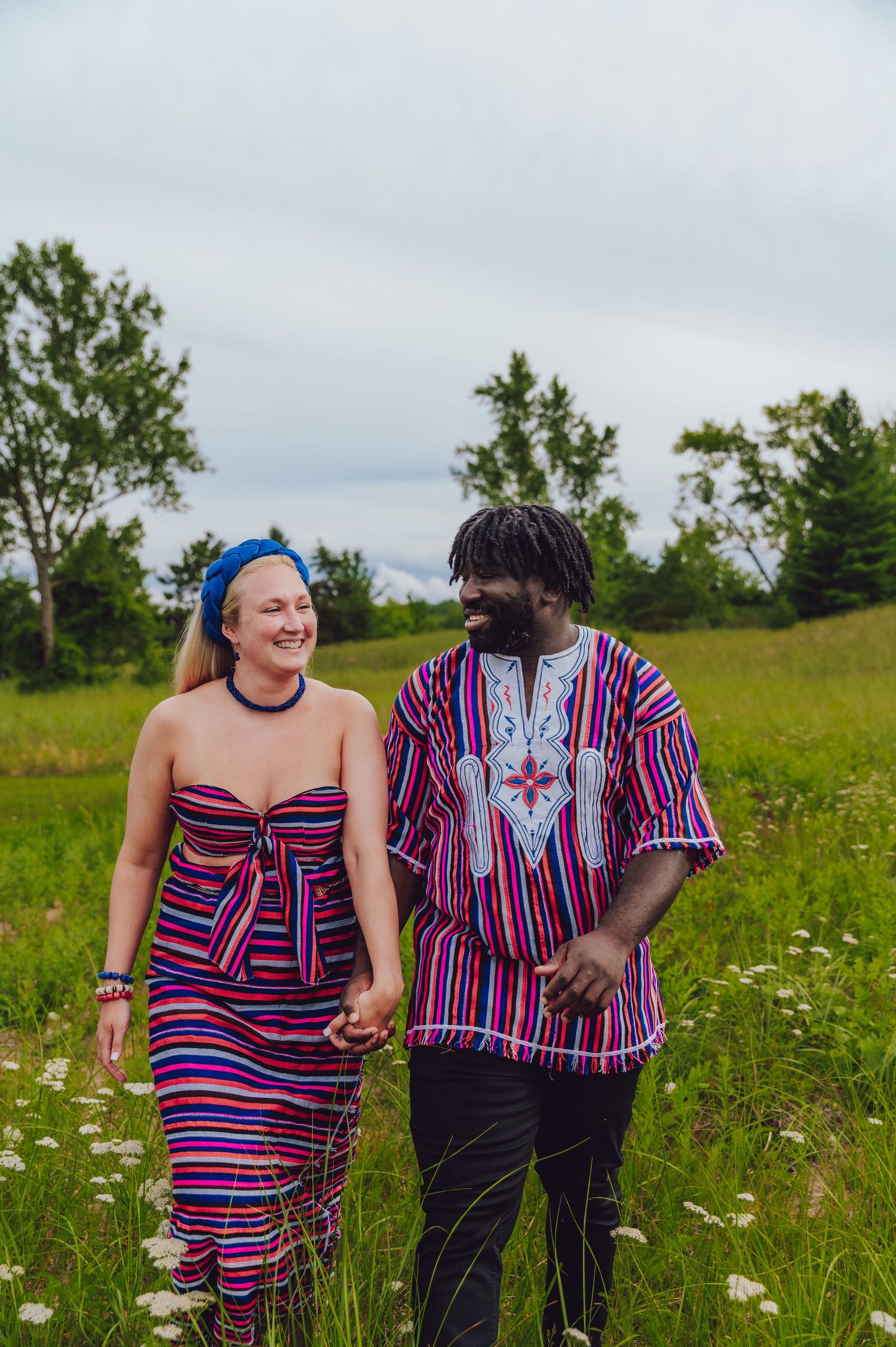 Couple walking through a meadow wearing vibrant matching striped outfits.