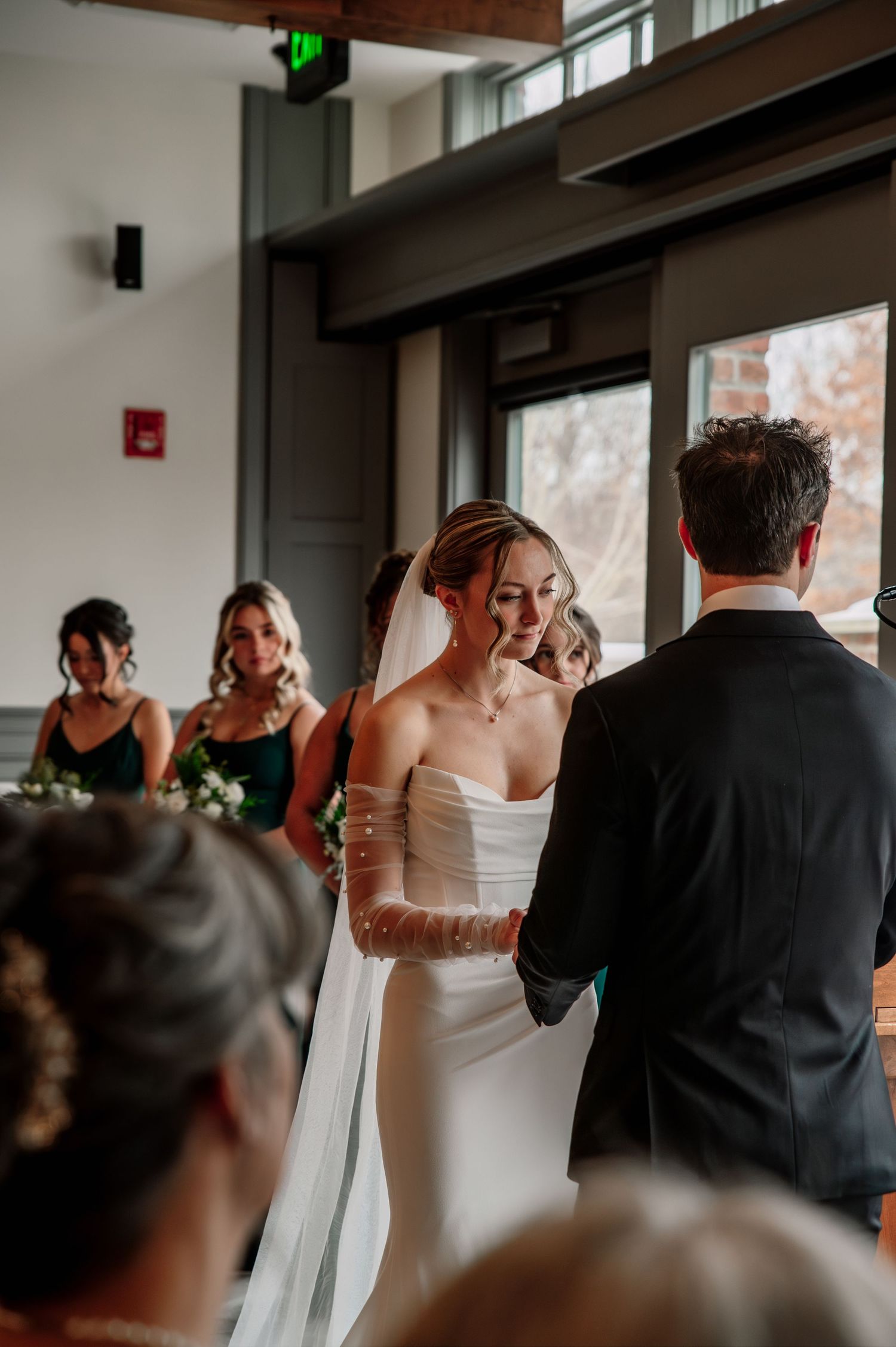 An indoor wedding ceremony with guests watching the couple exchange vows.