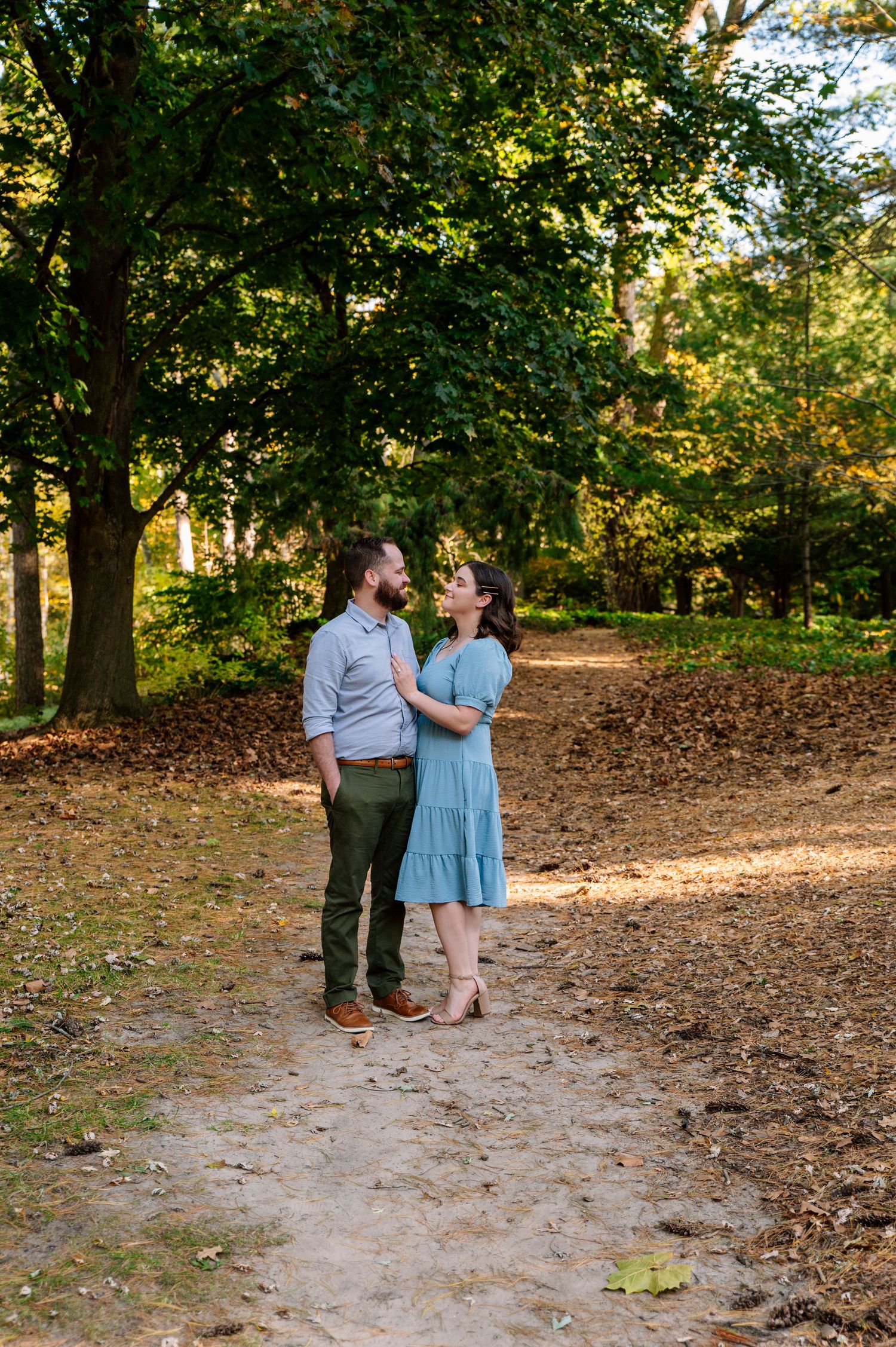 Couple sharing intimate moment on tree-lined autumn path during golden hour.