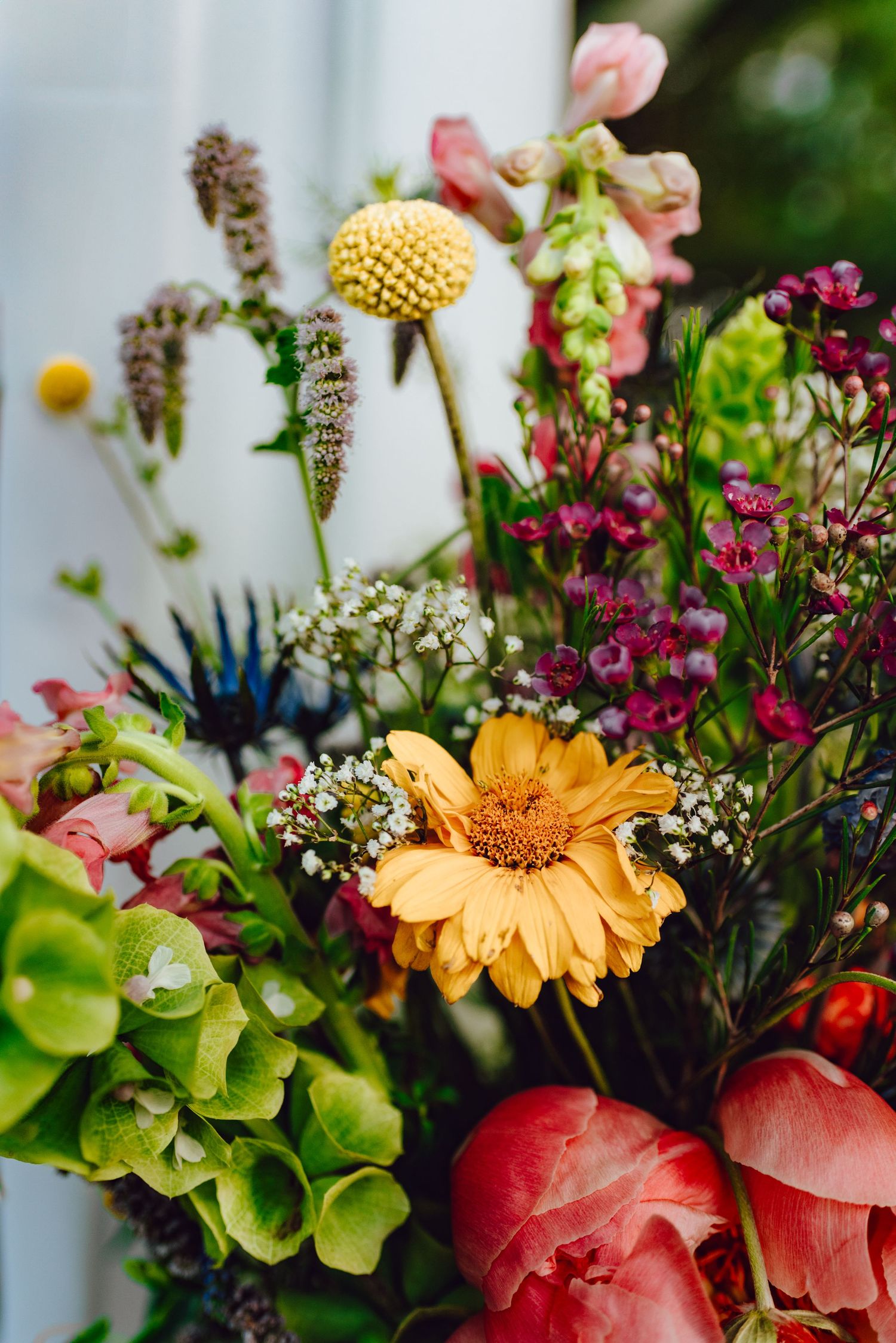 Fresh floral arrangement featuring pink roses, orange gerbera daisies, white baby's breath, and green foliage.